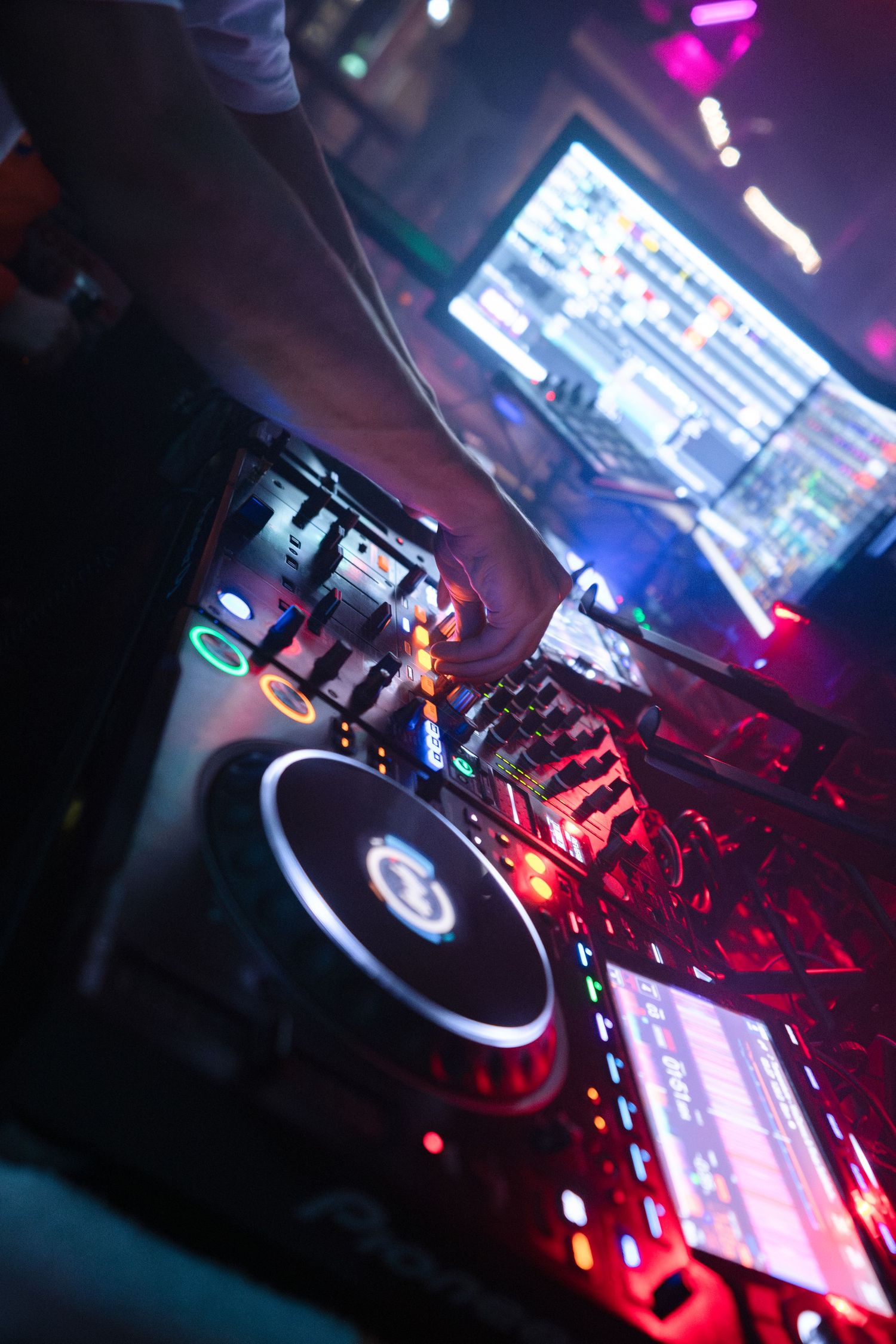 Close-up shots of DJ equipment and turntables illuminated by red and blue lighting in a nightclub setting.