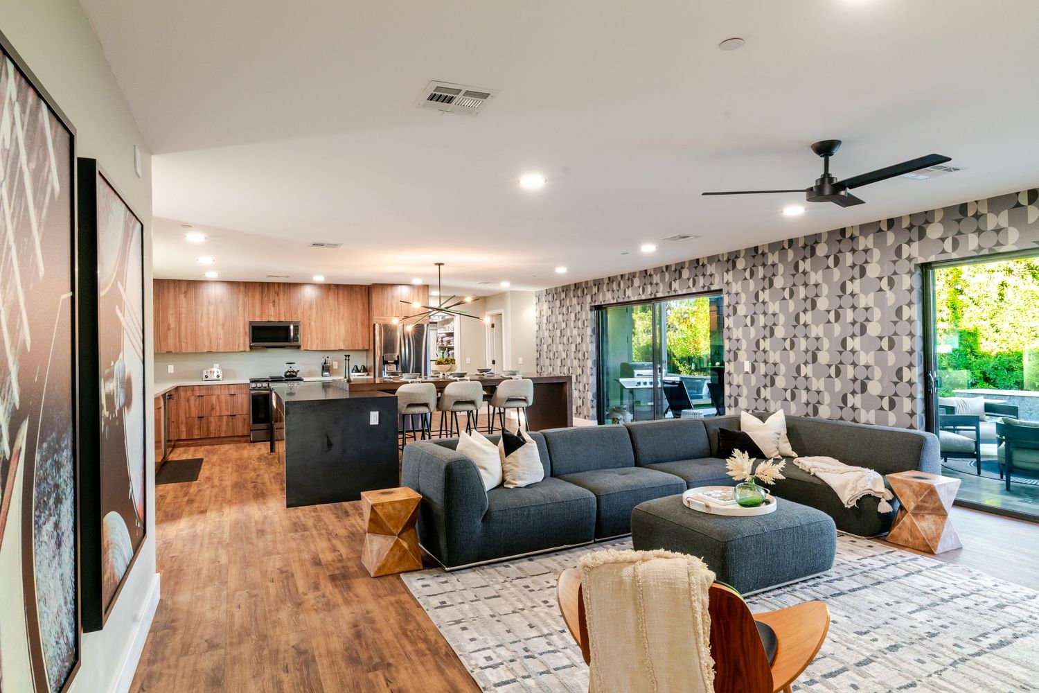 Modern living room interior with gray sectional sofa, black accent wall, and hardwood flooring in panoramic view.