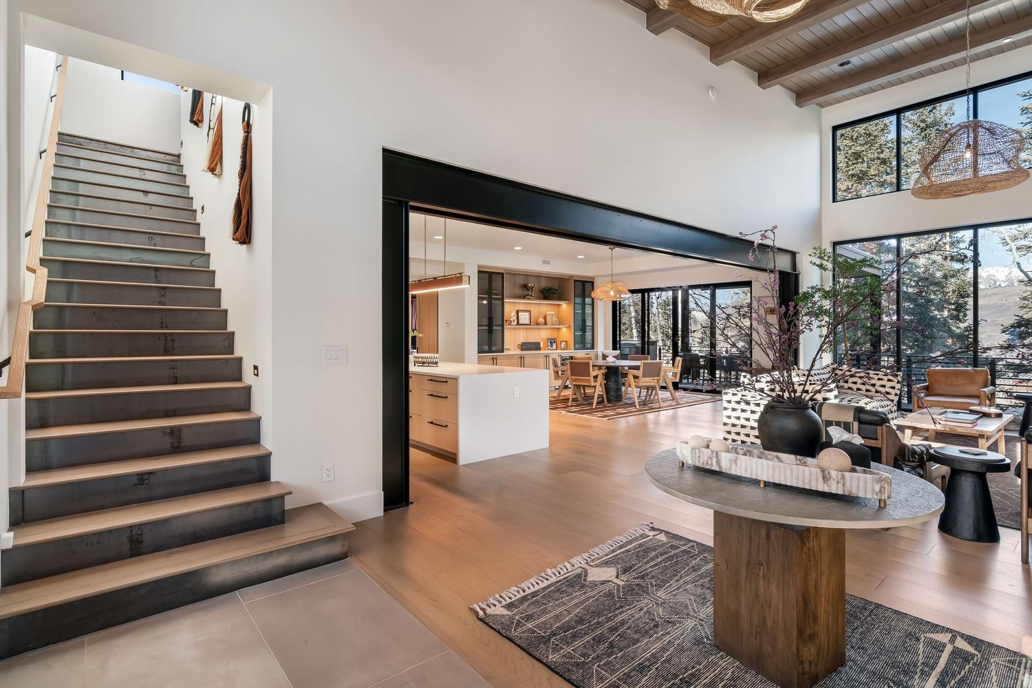 Modern interior staircase design with floating wooden treads and glass railings in a contemporary open-plan home.