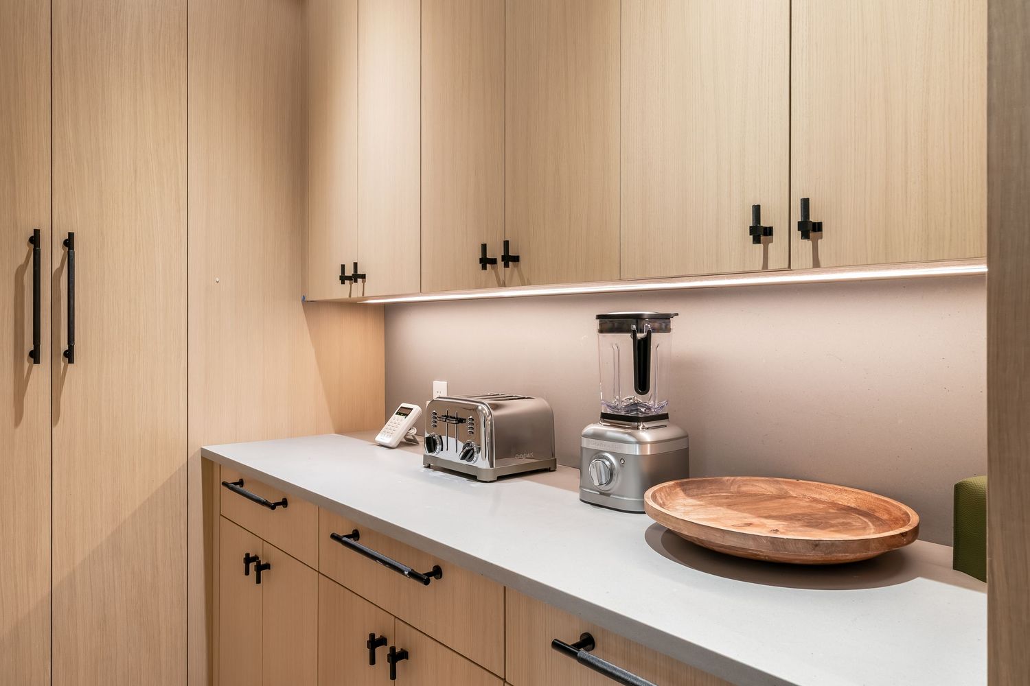 Modern white kitchen interior with wooden countertops, black hardware, and built-in appliances.