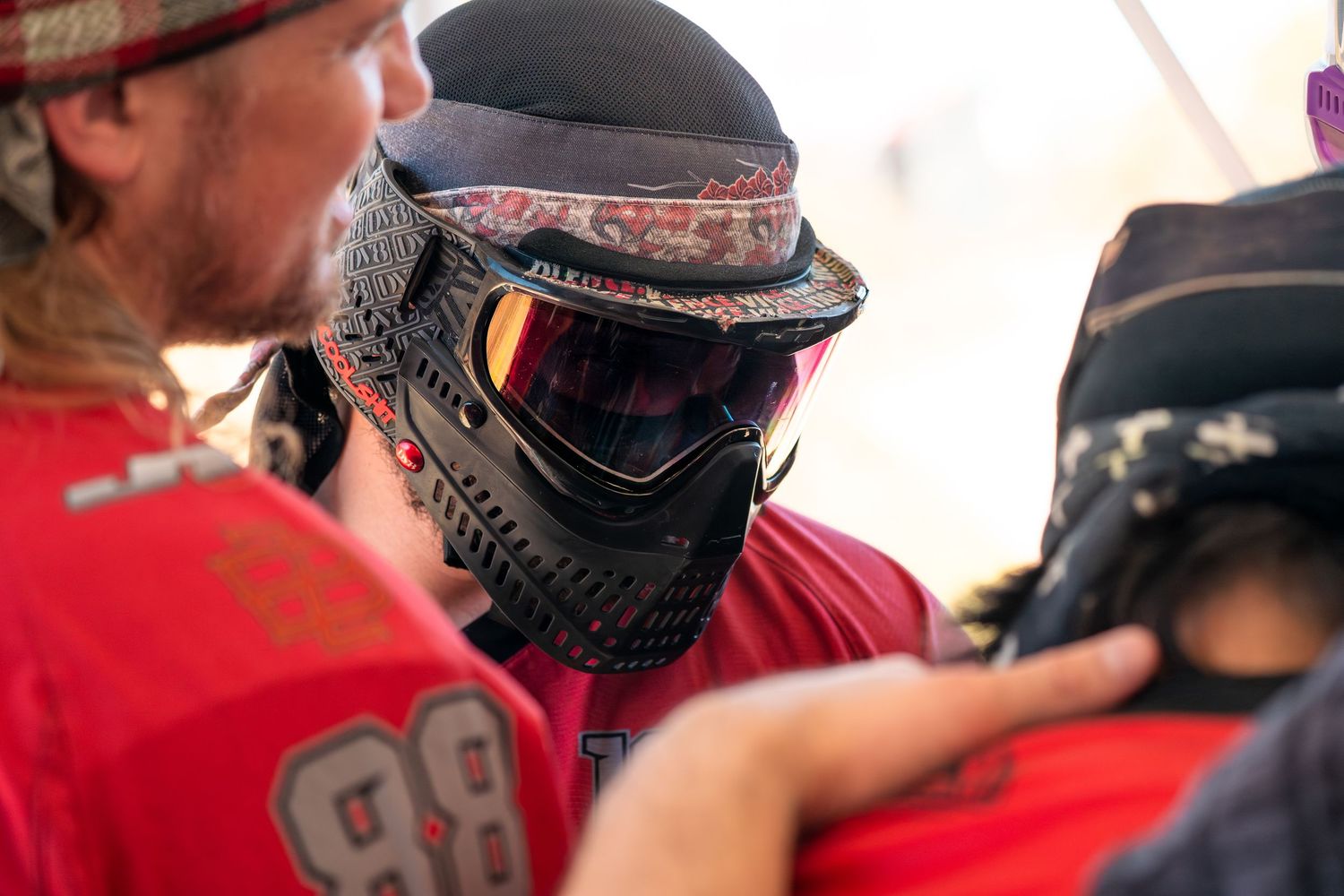Close-up of a paintball player wearing a black protective mask and helmet during a competitive game.