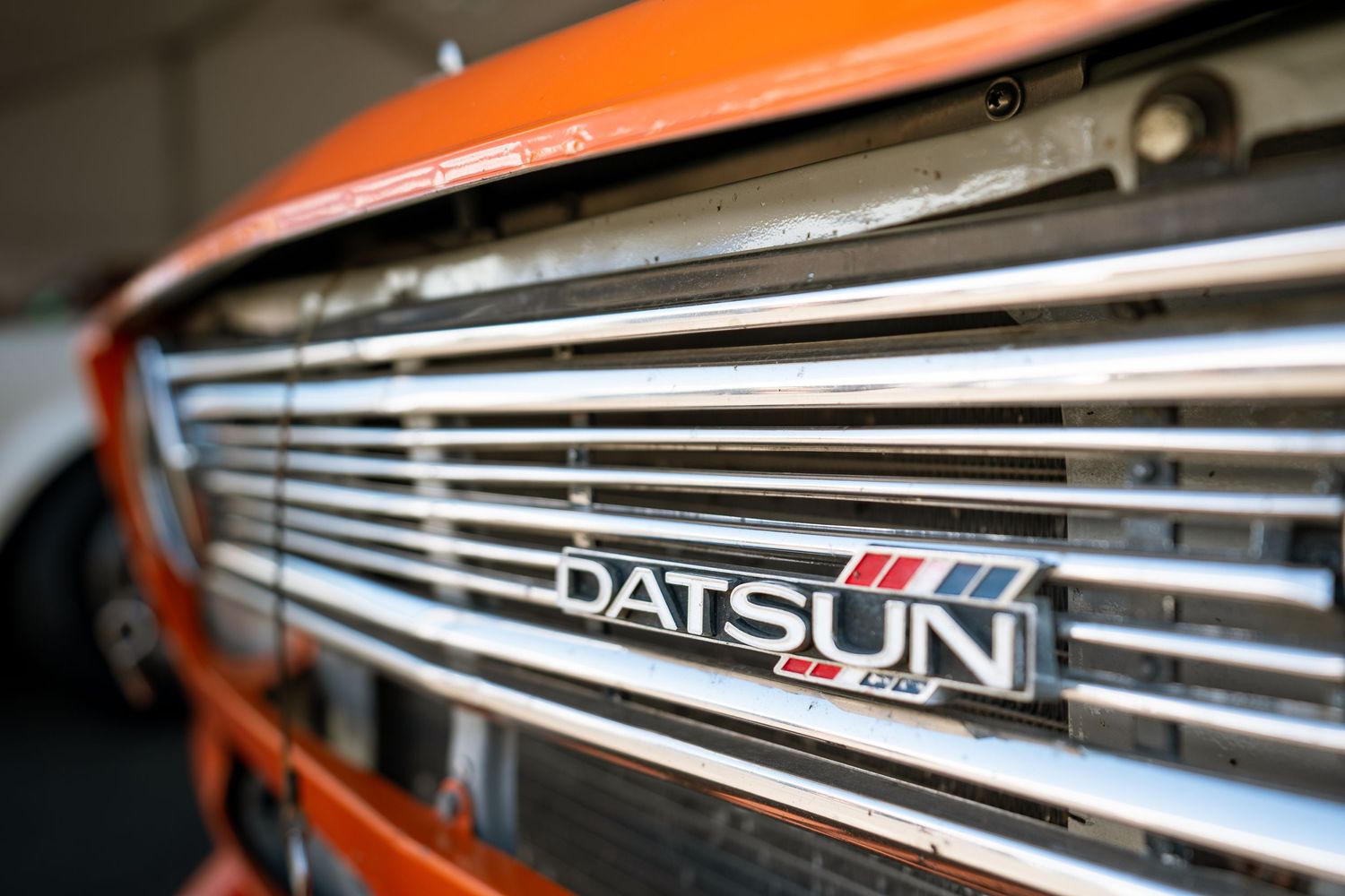 Close-up detail shot of chrome Datsun vehicle badging with reflective metallic finish.