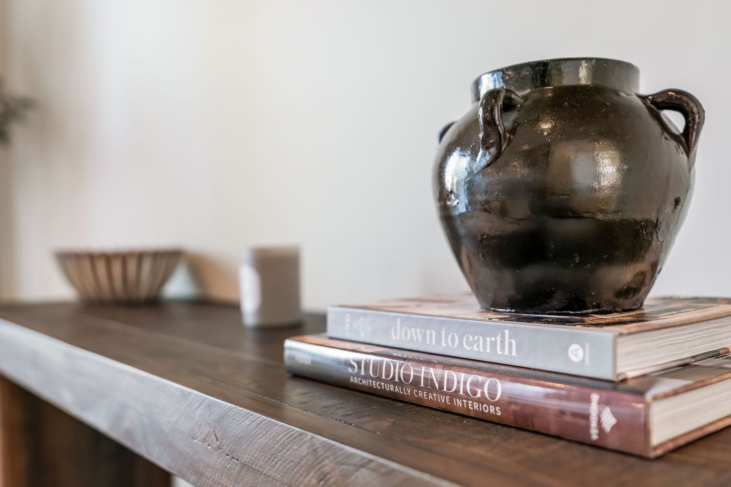Collection of decorative pottery and books arranged artistically on a wooden surface with soft lighting.