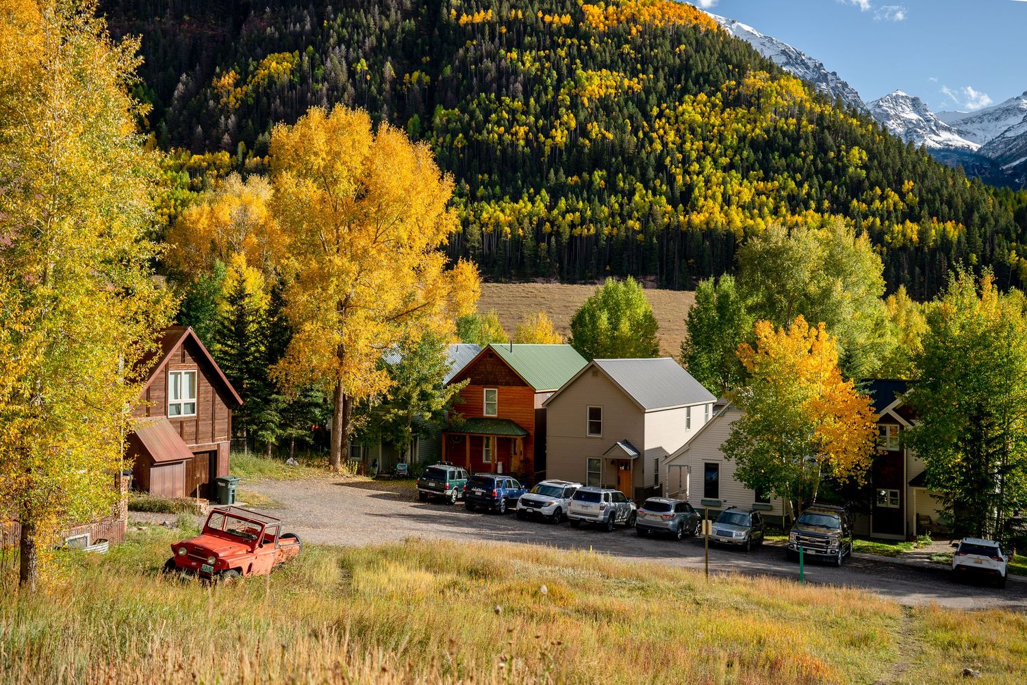 Historic mountain town with autumn foliage and distant snow-capped peaks.