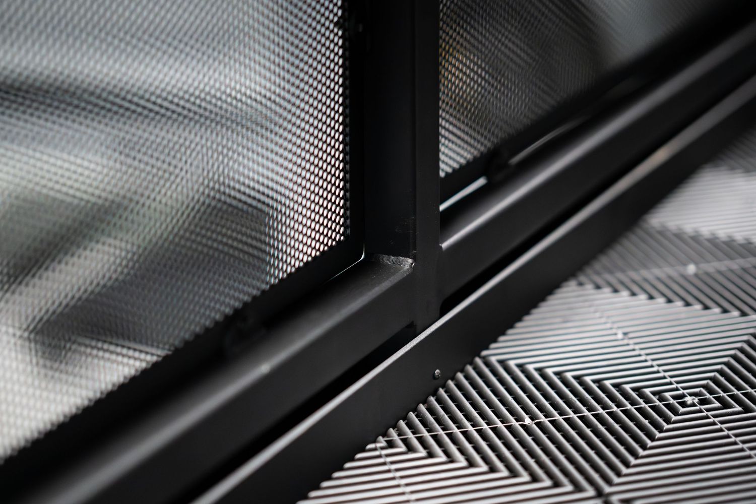 Abstract diagonal pattern of black metal frame against textured background.