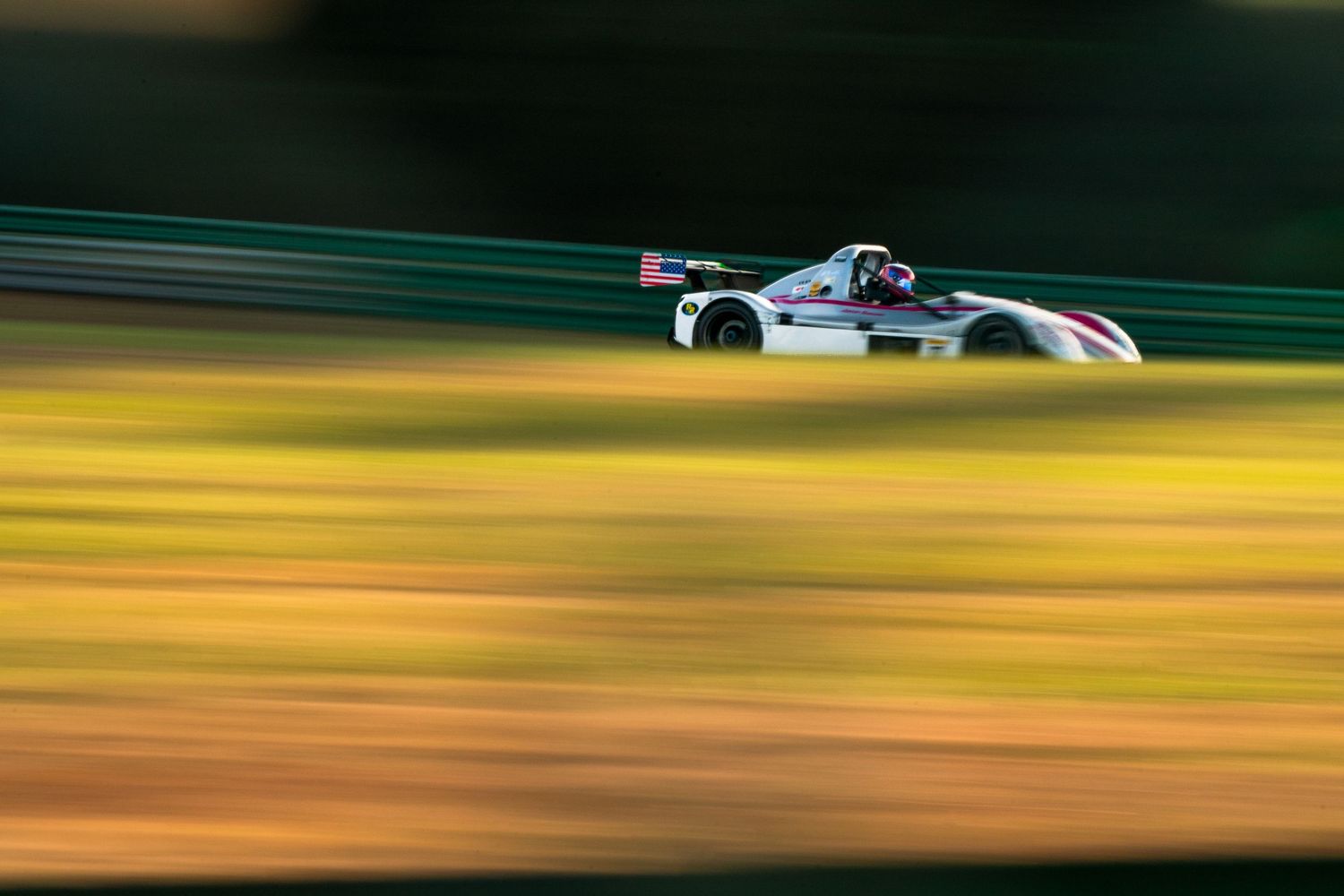 Formula 1 race car speeds past on track with motion blur effect creating vibrant streaks of color.