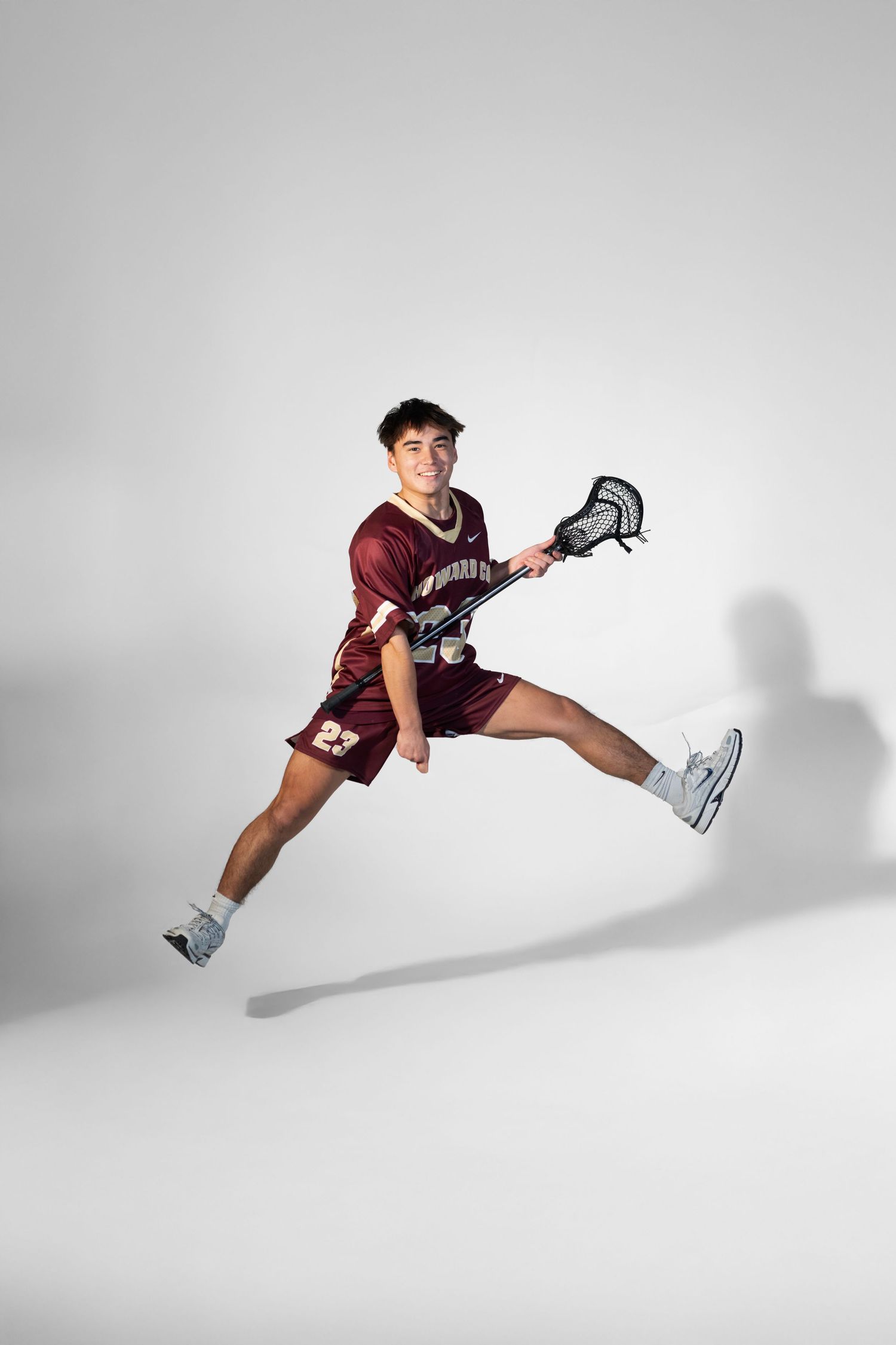 Dynamic sequence of a lacrosse player in maroon uniform jumping against white background.
