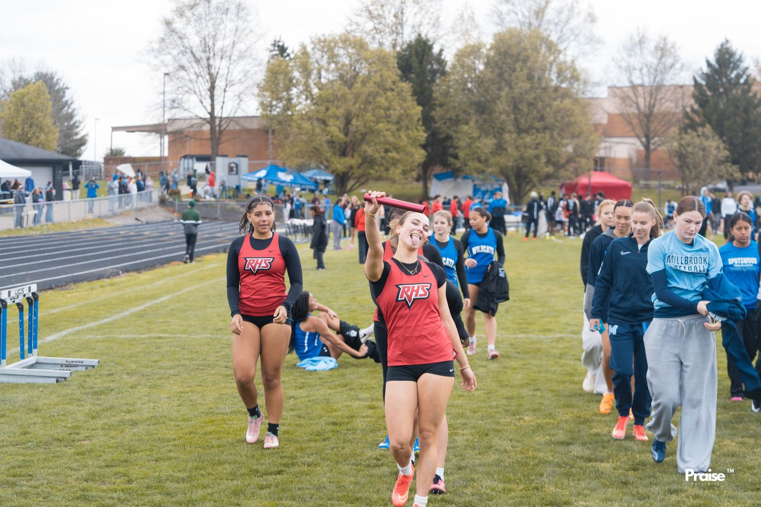 Athletes compete in an outdoor track and field event with spectators watching from the sidelines.