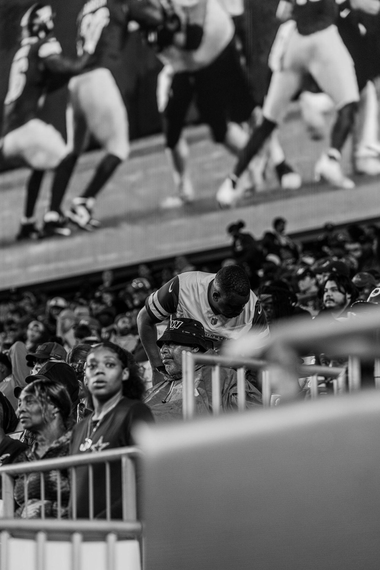 Black and white shot of fans watching intently from stadium seats.