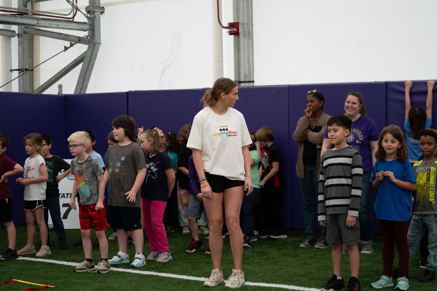 Students lined up along the wall of an indoor sports facility.