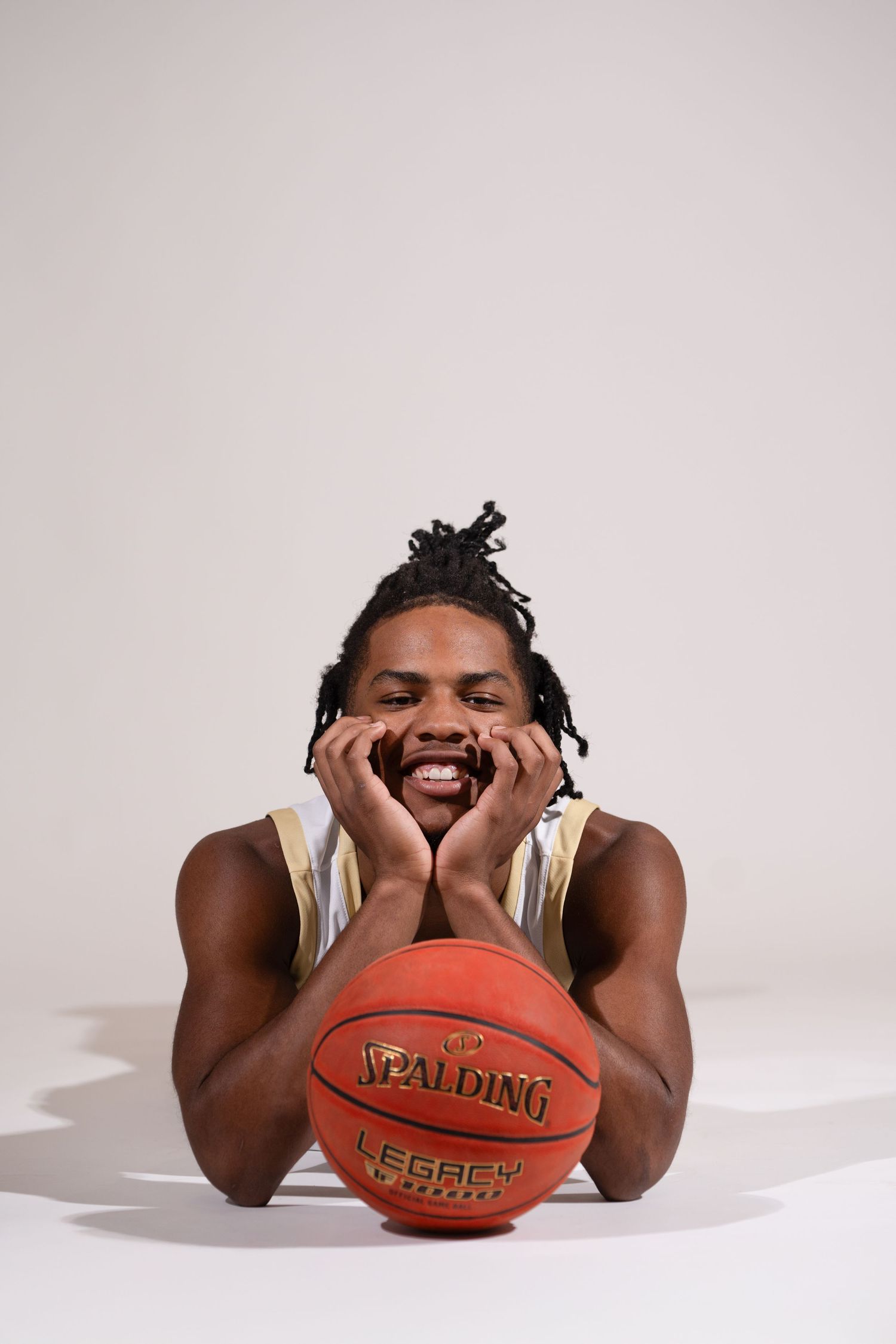 Basketball player posing playfully with a basketball on white background.