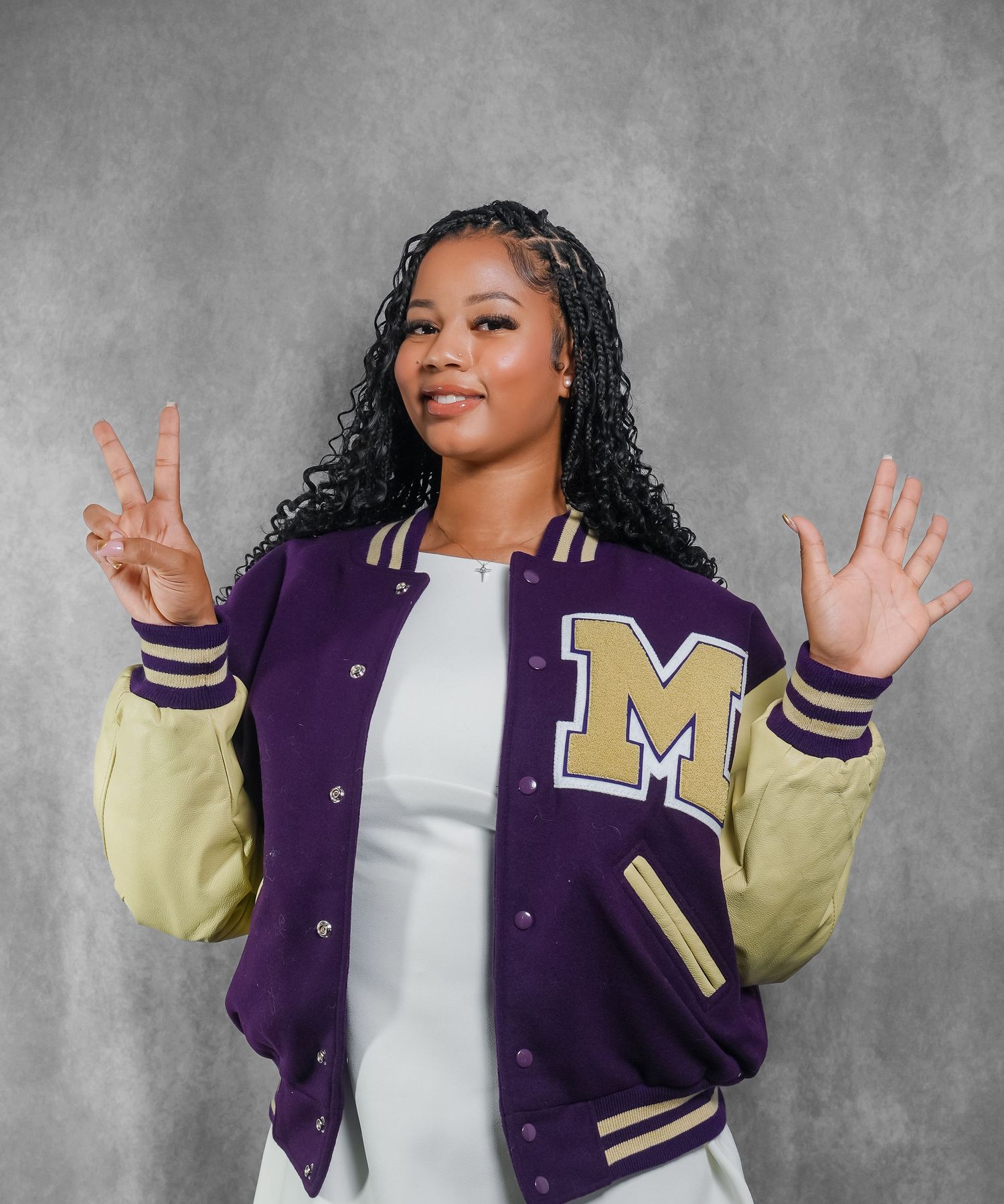 Stylish purple and yellow varsity letterman jacket modeled against grey background.
