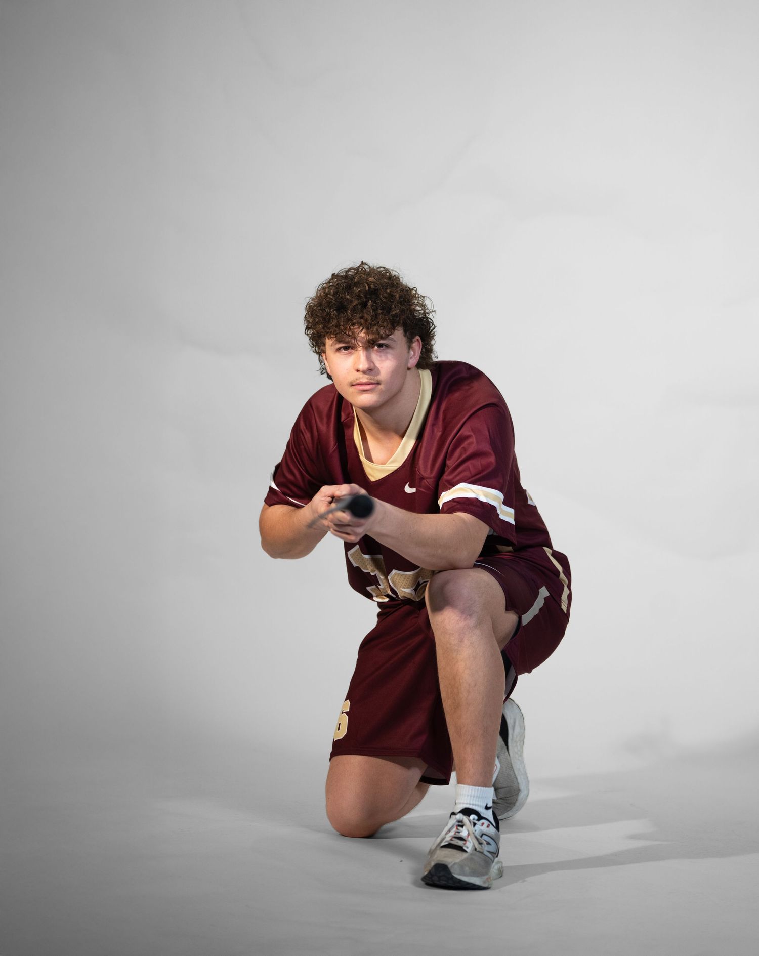 Athletic figure in maroon uniform demonstrates low defensive stance on white background.