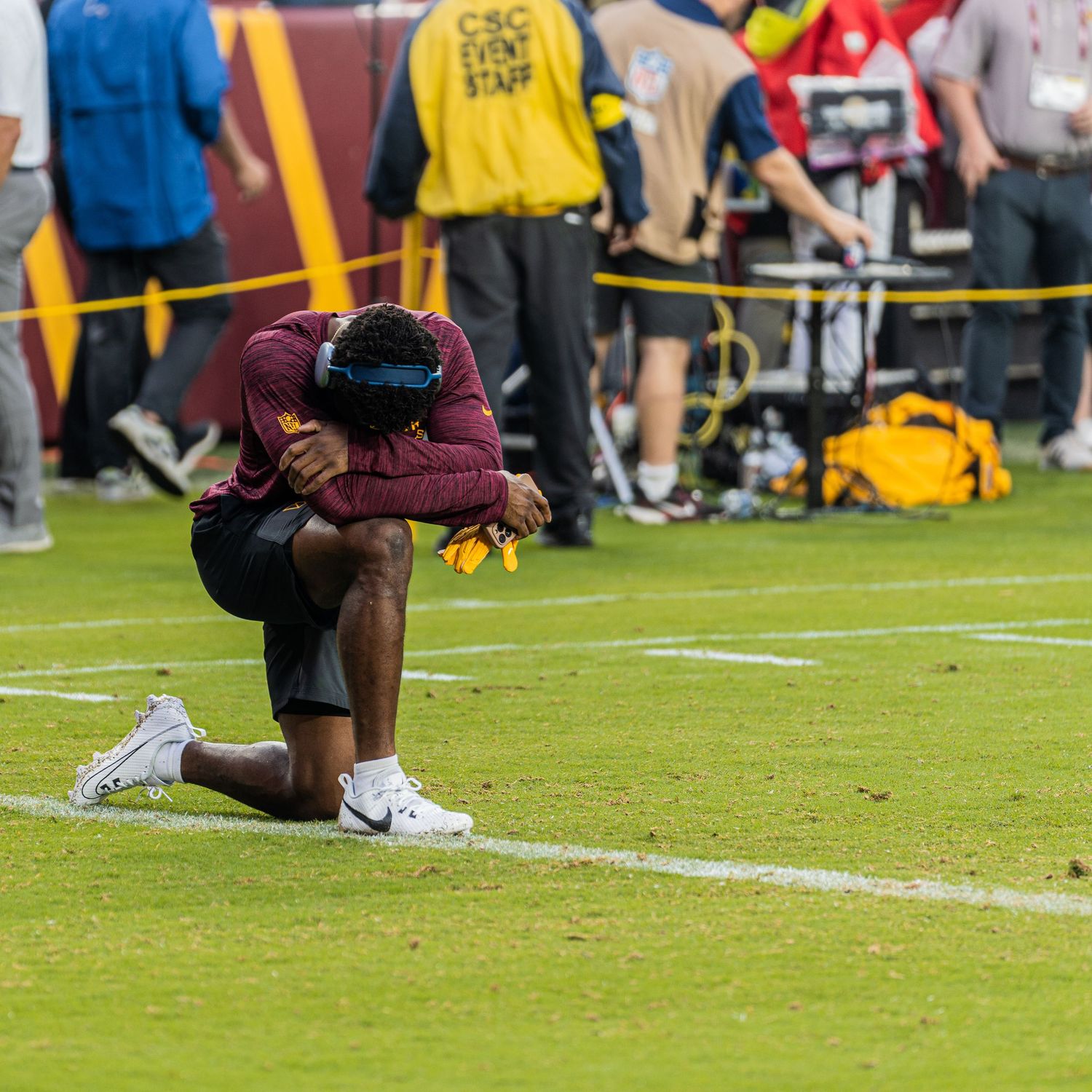 Athletes warming up on football field with yellow goal posts visible in background.