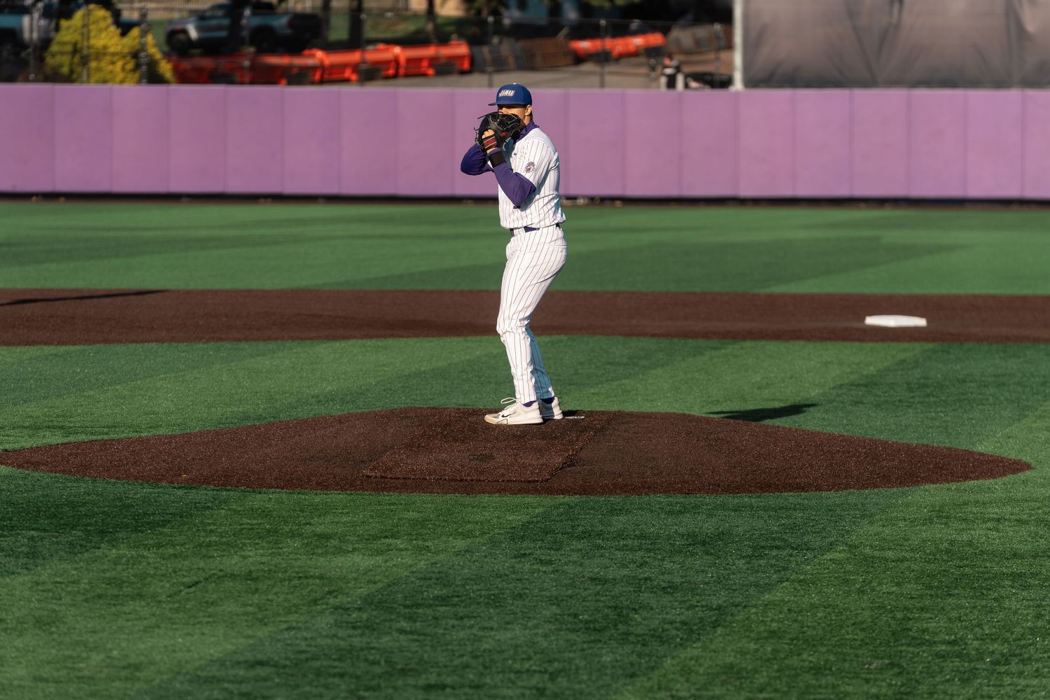 Baseball players warming up on a well-maintained baseball diamond during daytime practice.