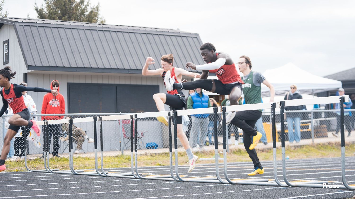 Track athletes practicing hurdle jumps during an outdoor training session.
