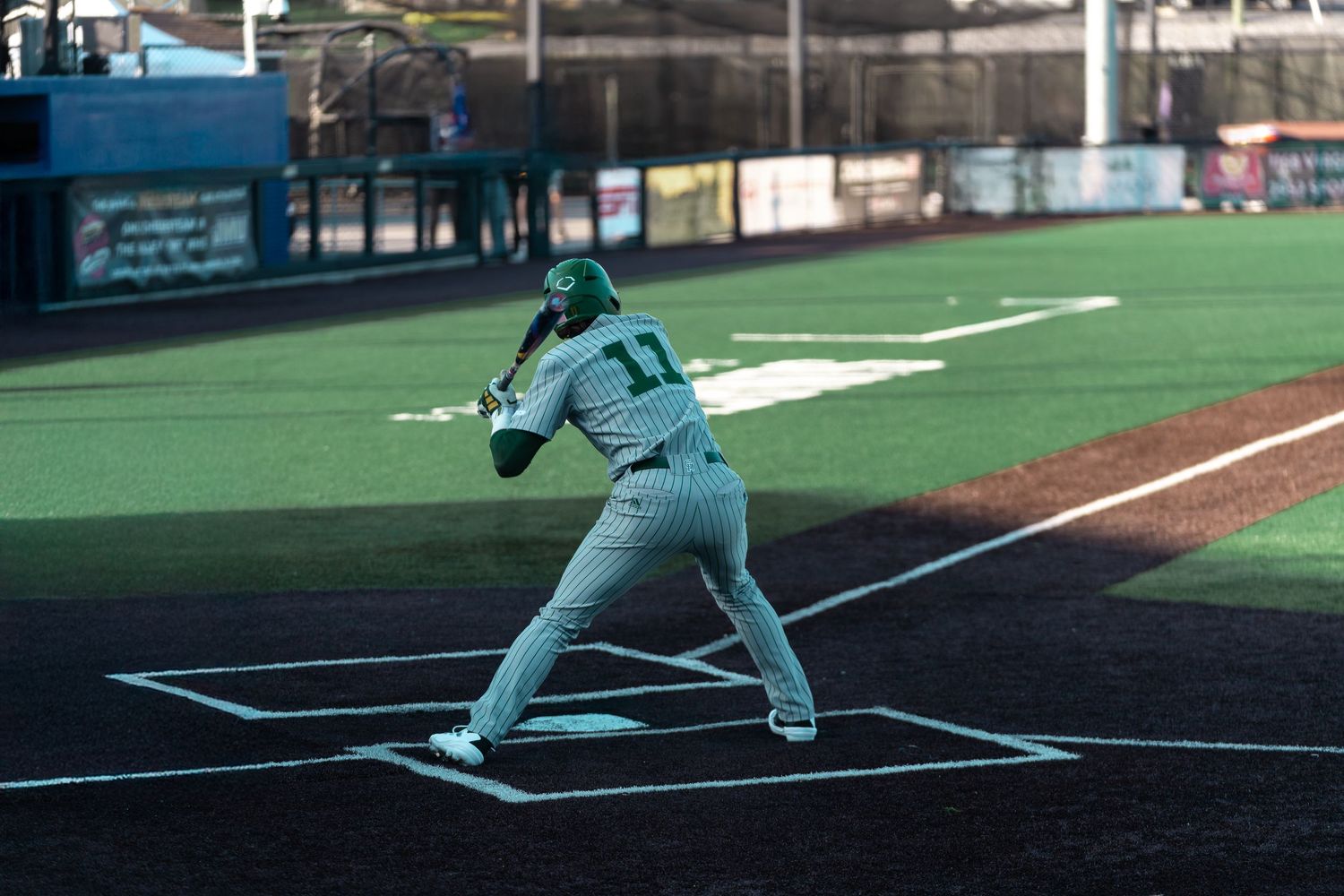 Baseball player in white uniform practicing batting stance at home plate.