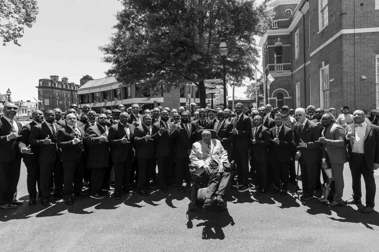 Large group poses together for formal outdoor photograph in black and white.