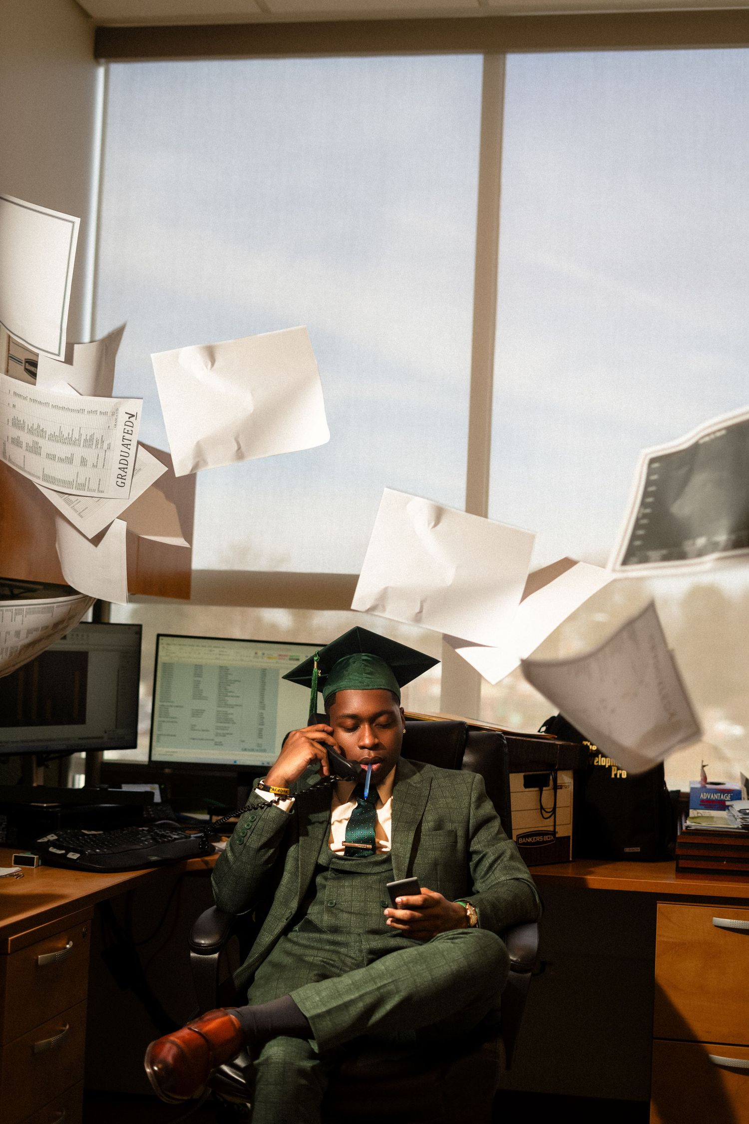 Professional in green attire sitting at desk with floating papers in modern office setting.