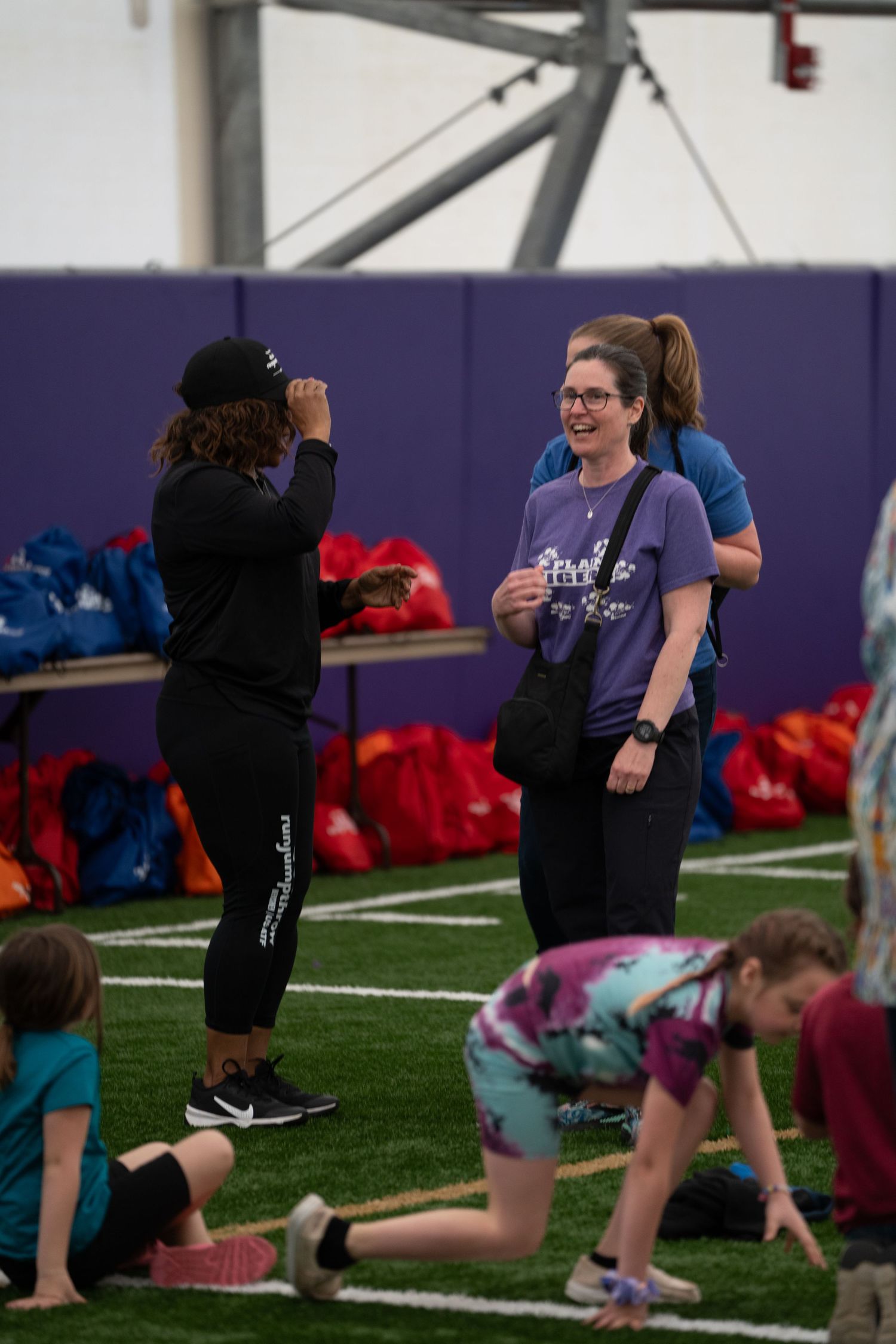 Athletes exercising in an indoor sports facility with purple walls.