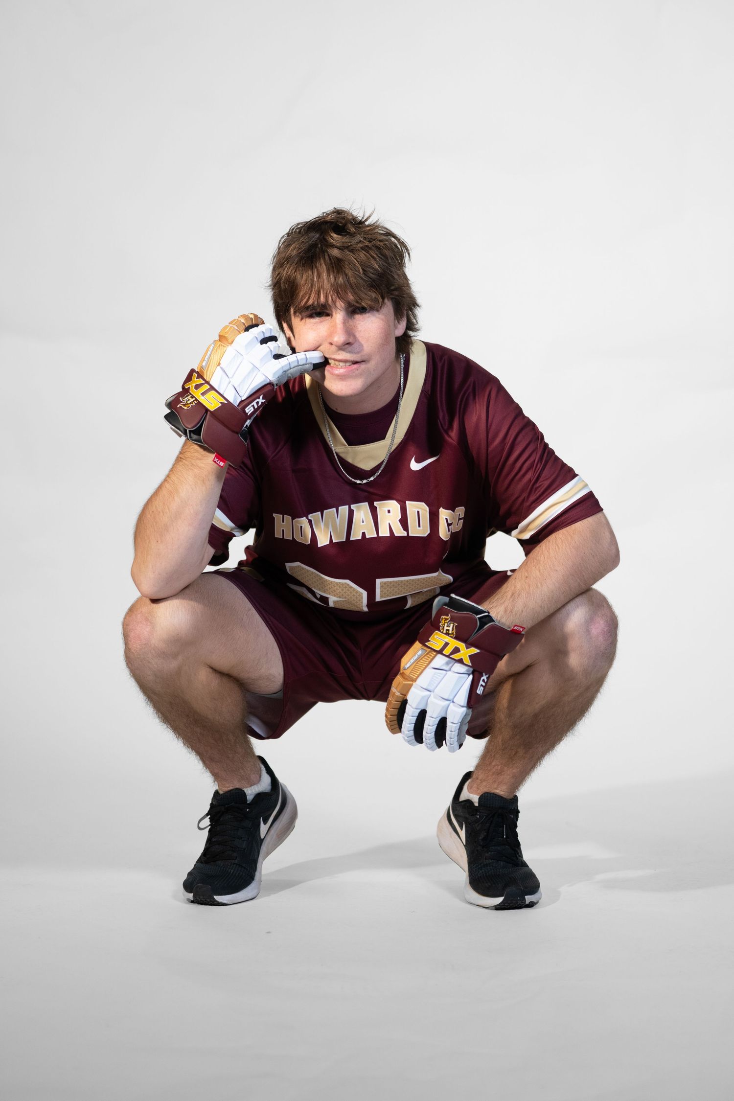 Athlete in maroon Howard jersey demonstrates crouching position against white backdrop.