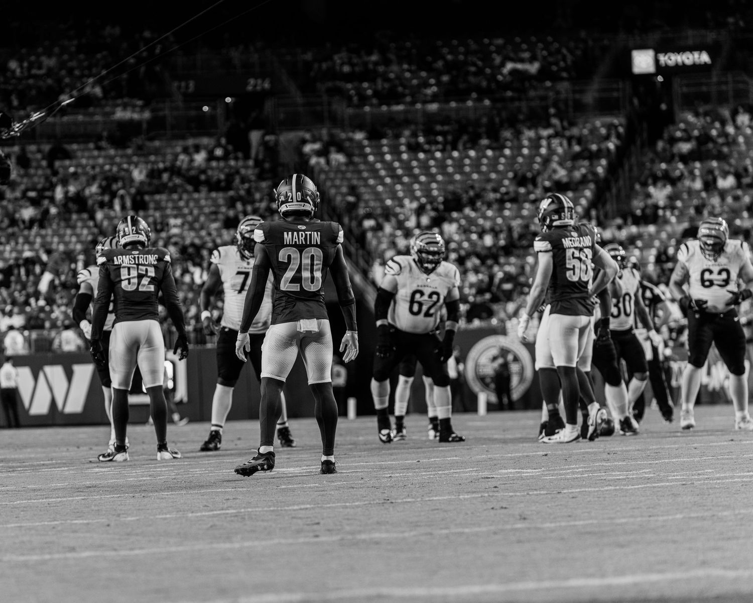 Black and white wide shot of football players lined up for a play on the field.
