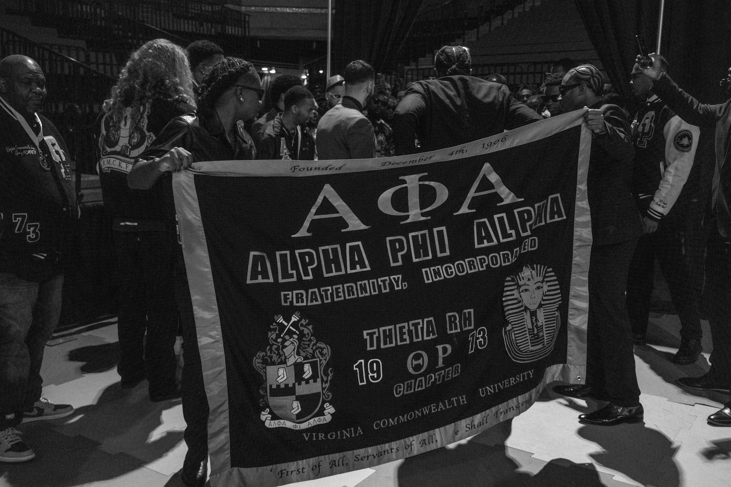 Black and white image of people holding banners at a gathering.
