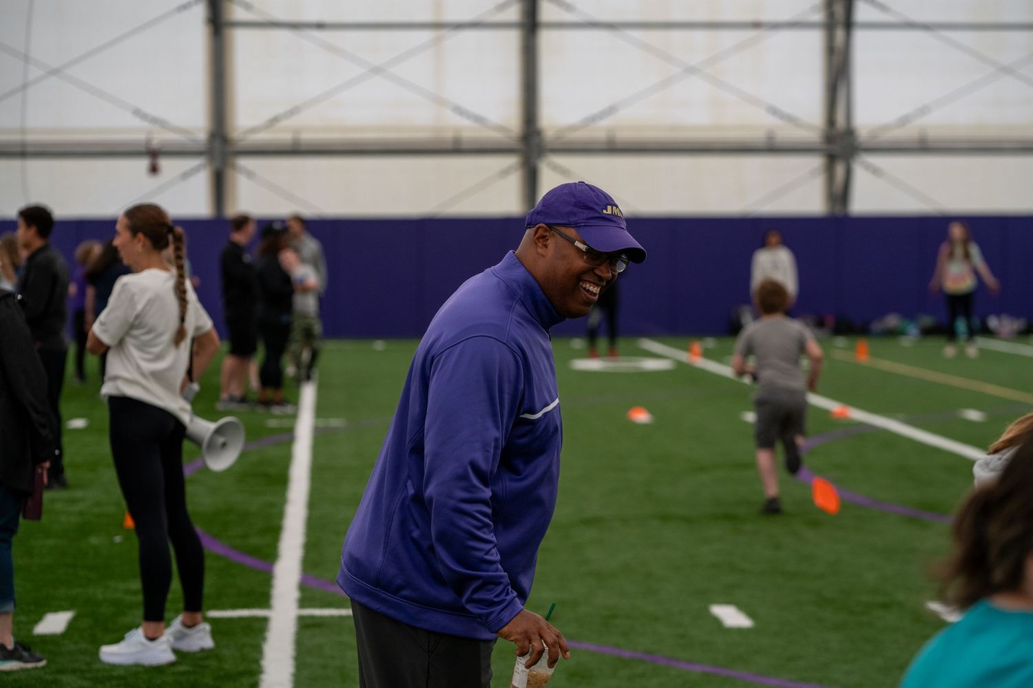 Participants gathering in an indoor sports facility with artificial turf.