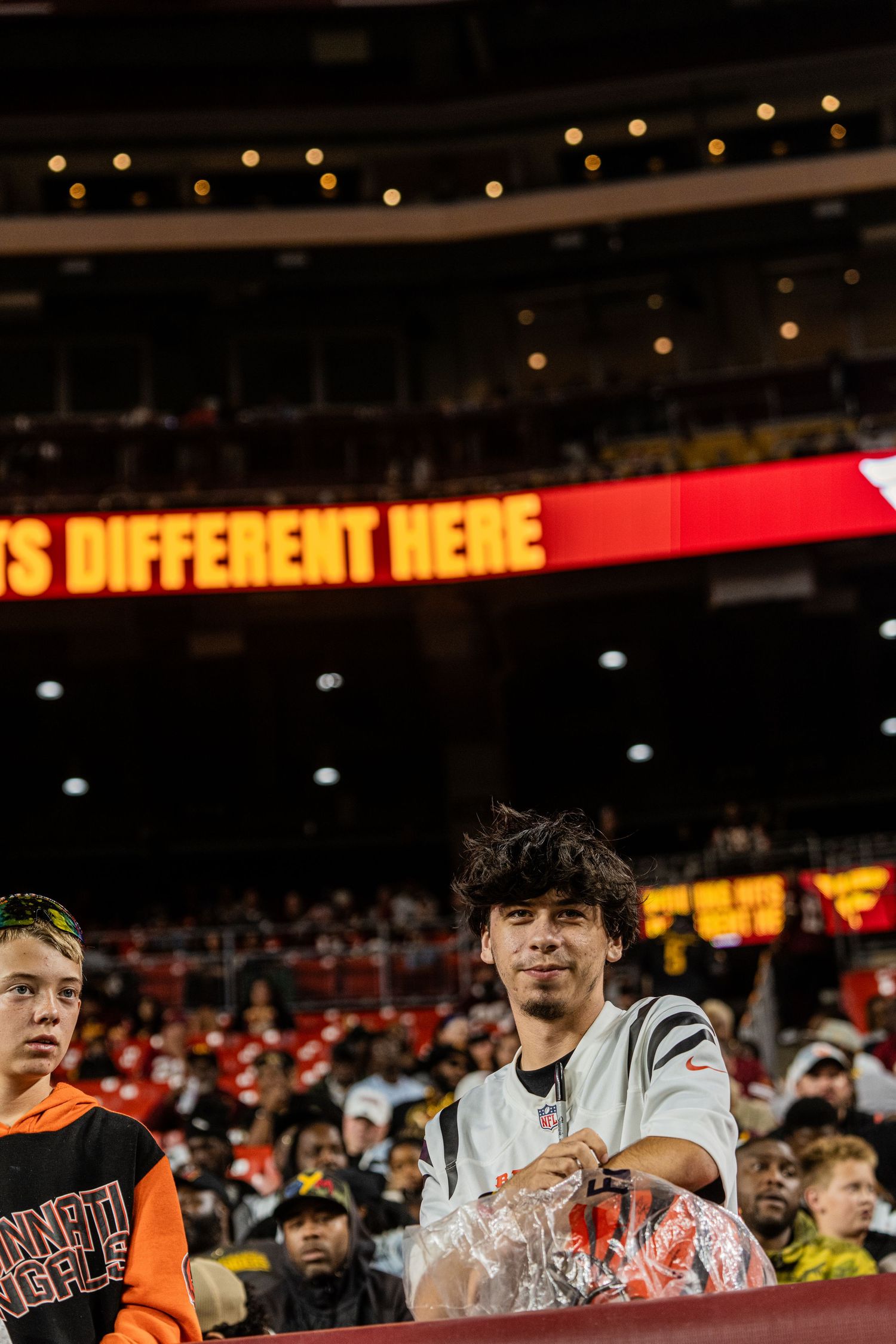 Sports fans fill the stadium stands beneath an illuminated display board.