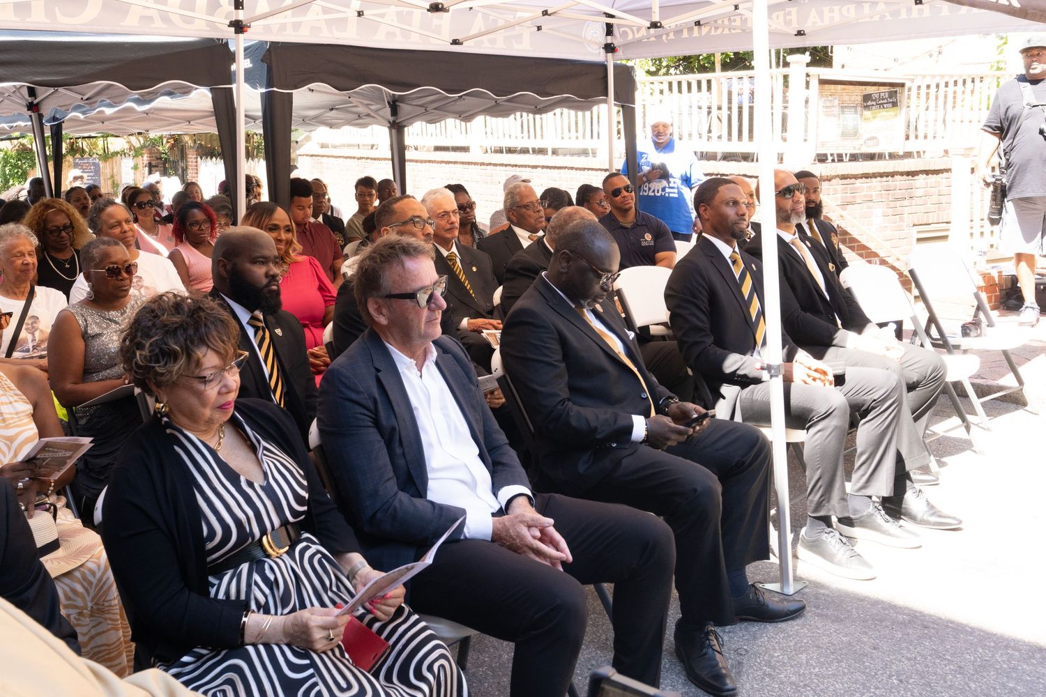 Large crowd seated in rows at an indoor event or ceremony.