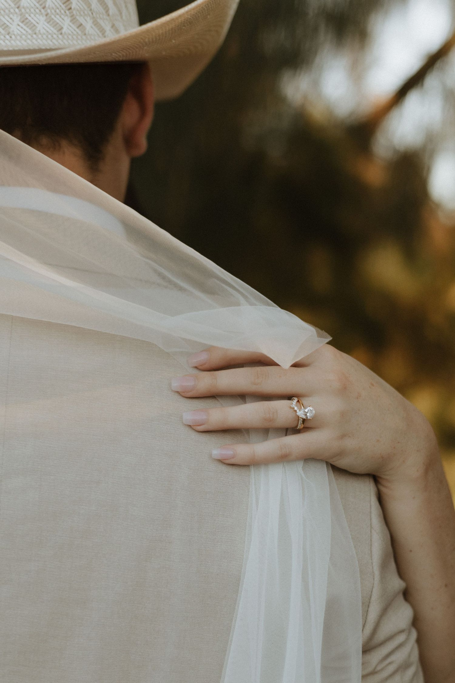 Close-up of hands touching soft white fabric with an engagement ring visible.