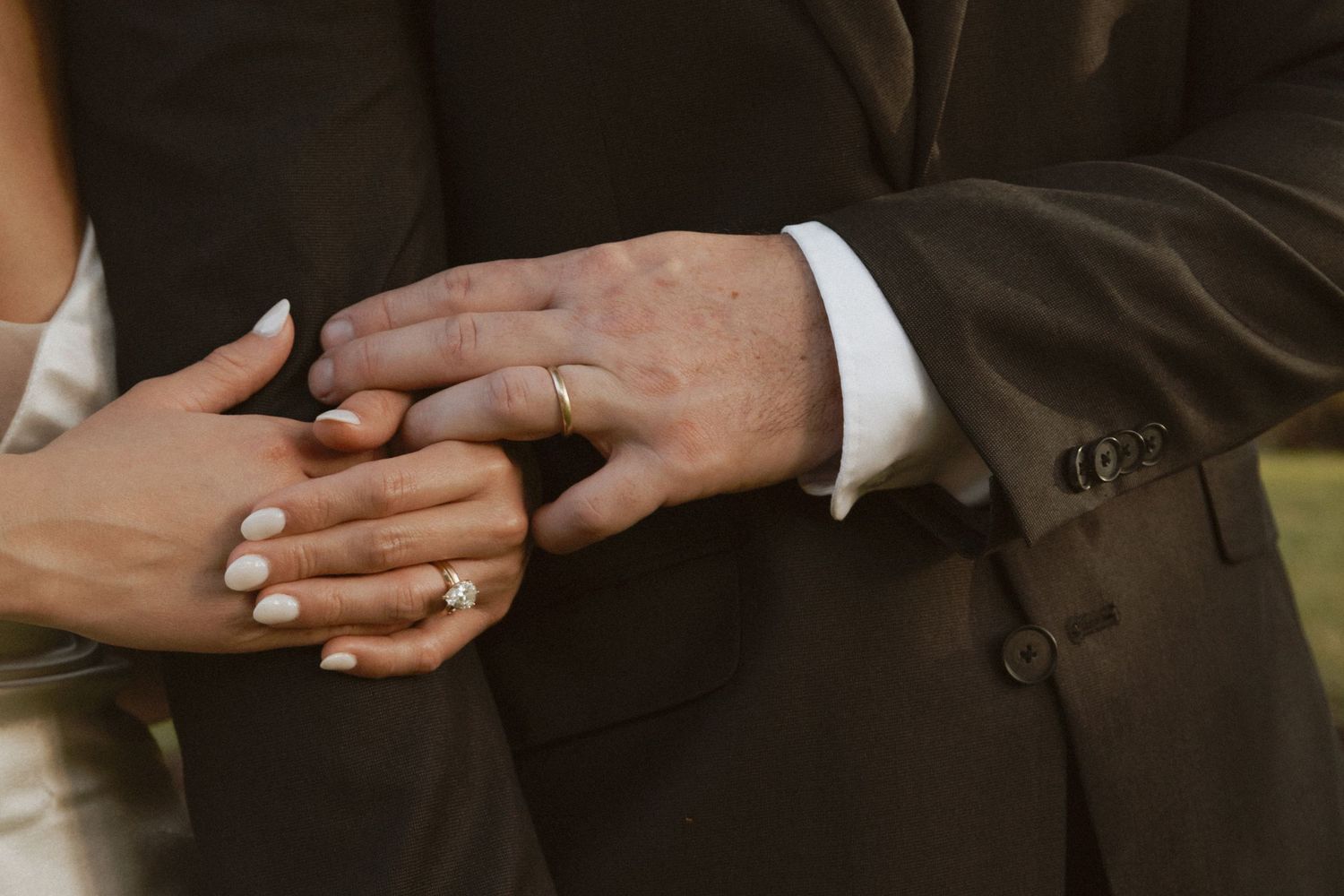Close-up view of hands with wedding rings touching intimately.