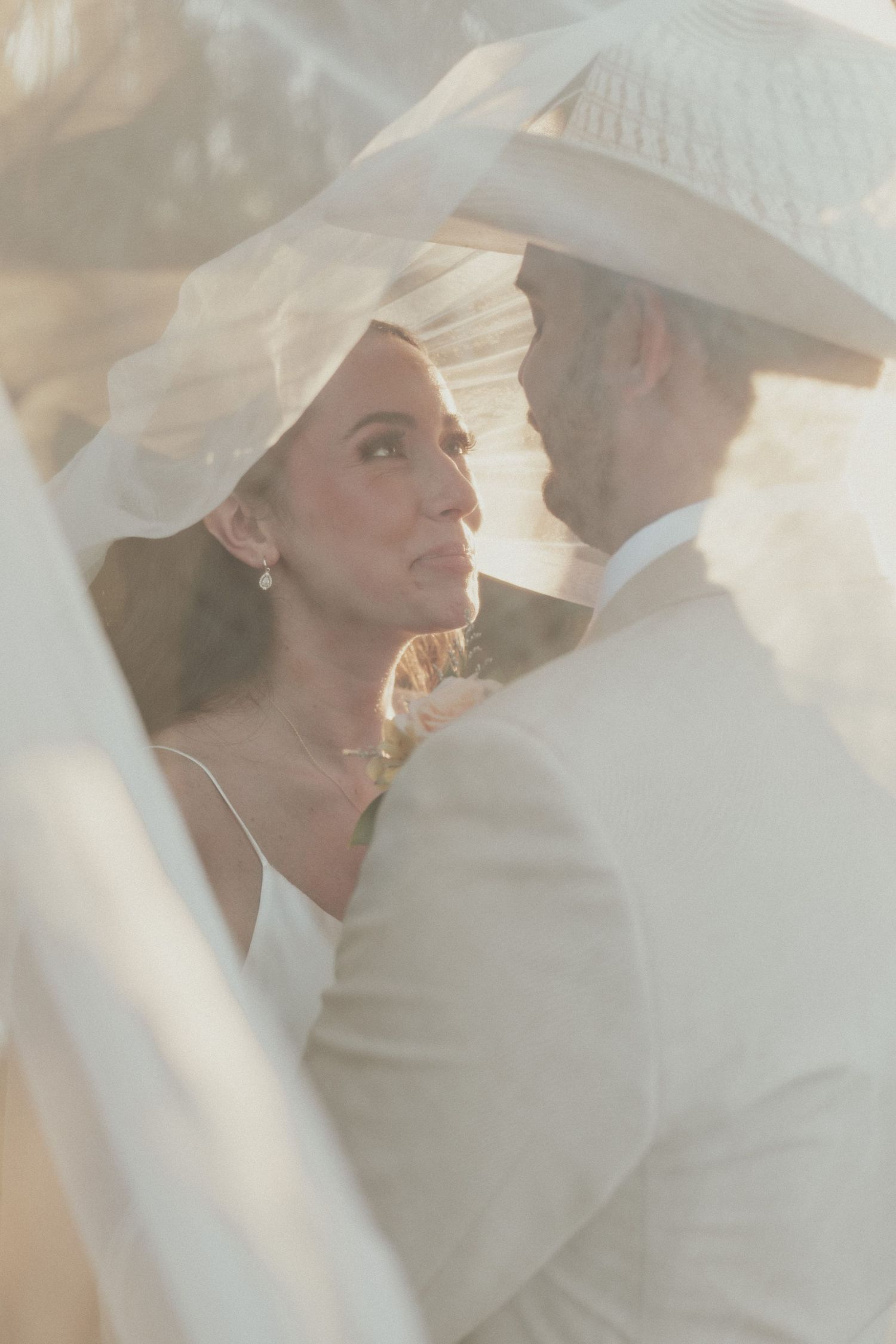 Ethereal wedding portrait with soft lighting and white cowboy hats creating a romantic atmosphere.