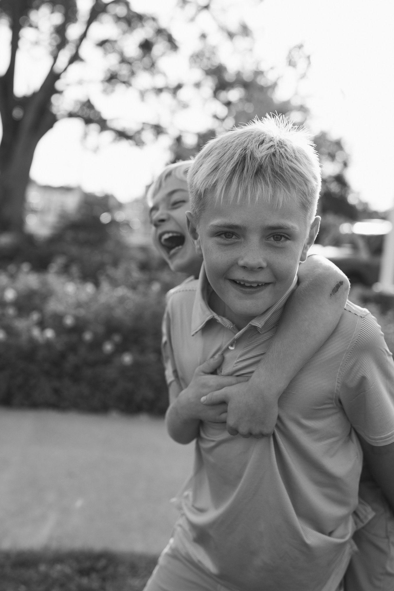 Black and white photo series showing playful expressions and laughter in an outdoor setting.
