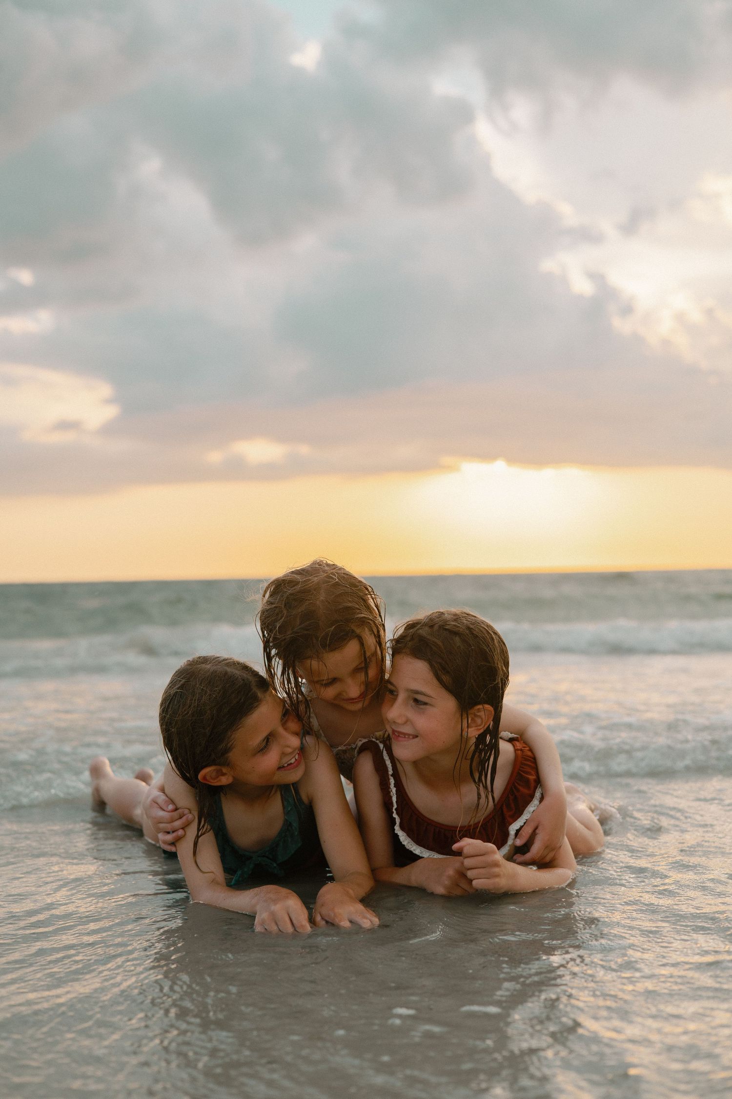 Children playing in ocean waves during a beautiful sunset.