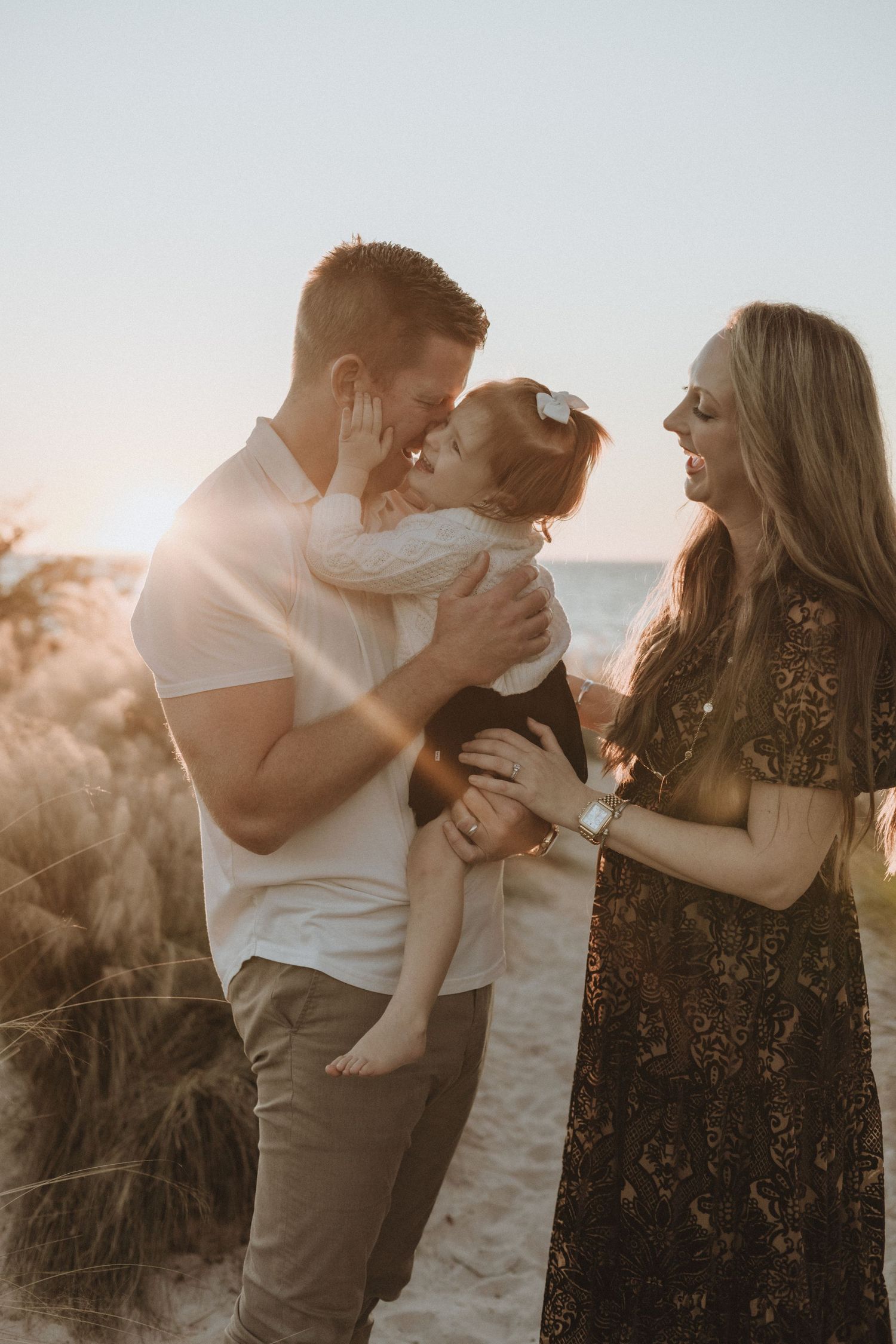 Family sharing intimate embraces during sunset beach photoshoot.