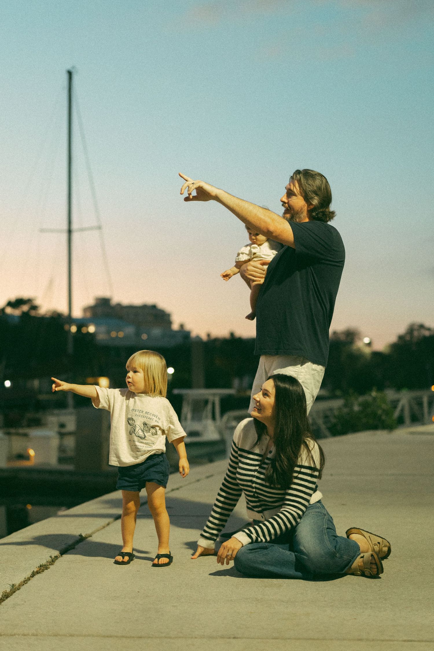 Two friends in casual wear strike dynamic pointing poses together on a concrete surface at sunset.