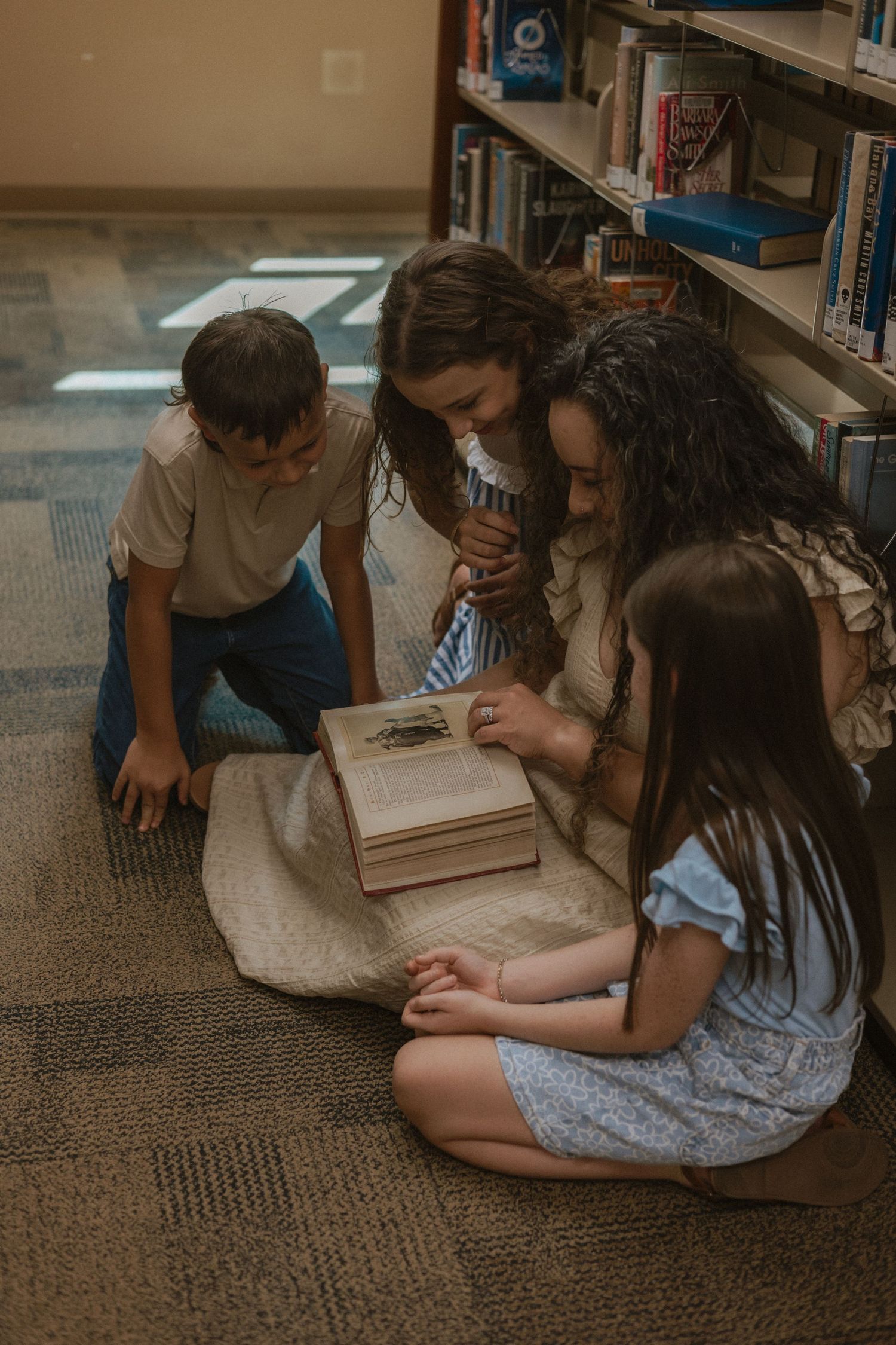 Group reading books together on carpeted floor in casual setting.