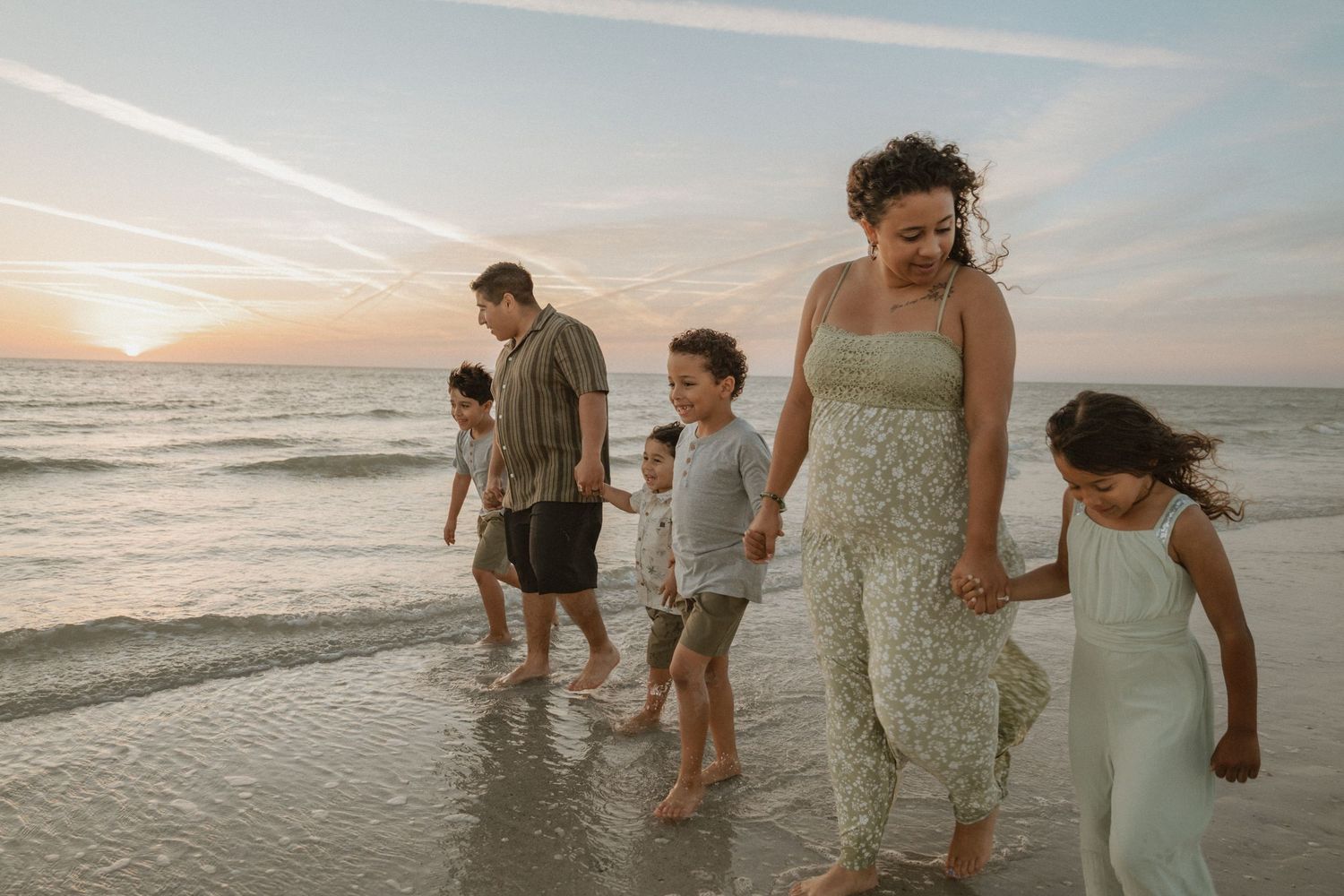 Family walking together along the ocean shore at sunset.