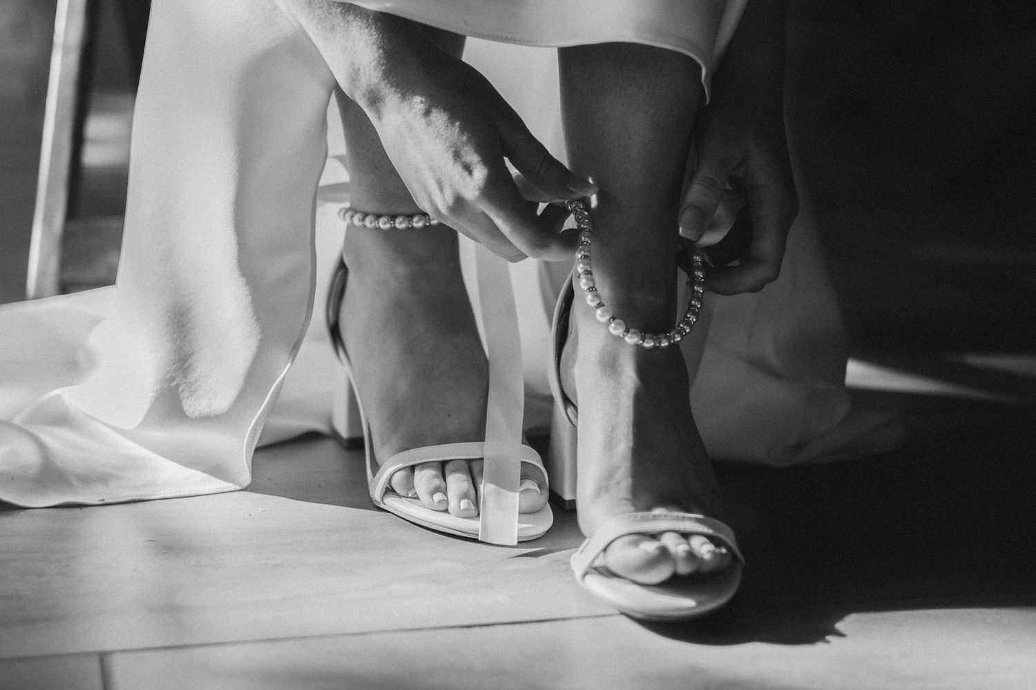 Artistic black and white detail shot of wedding shoes and feet.