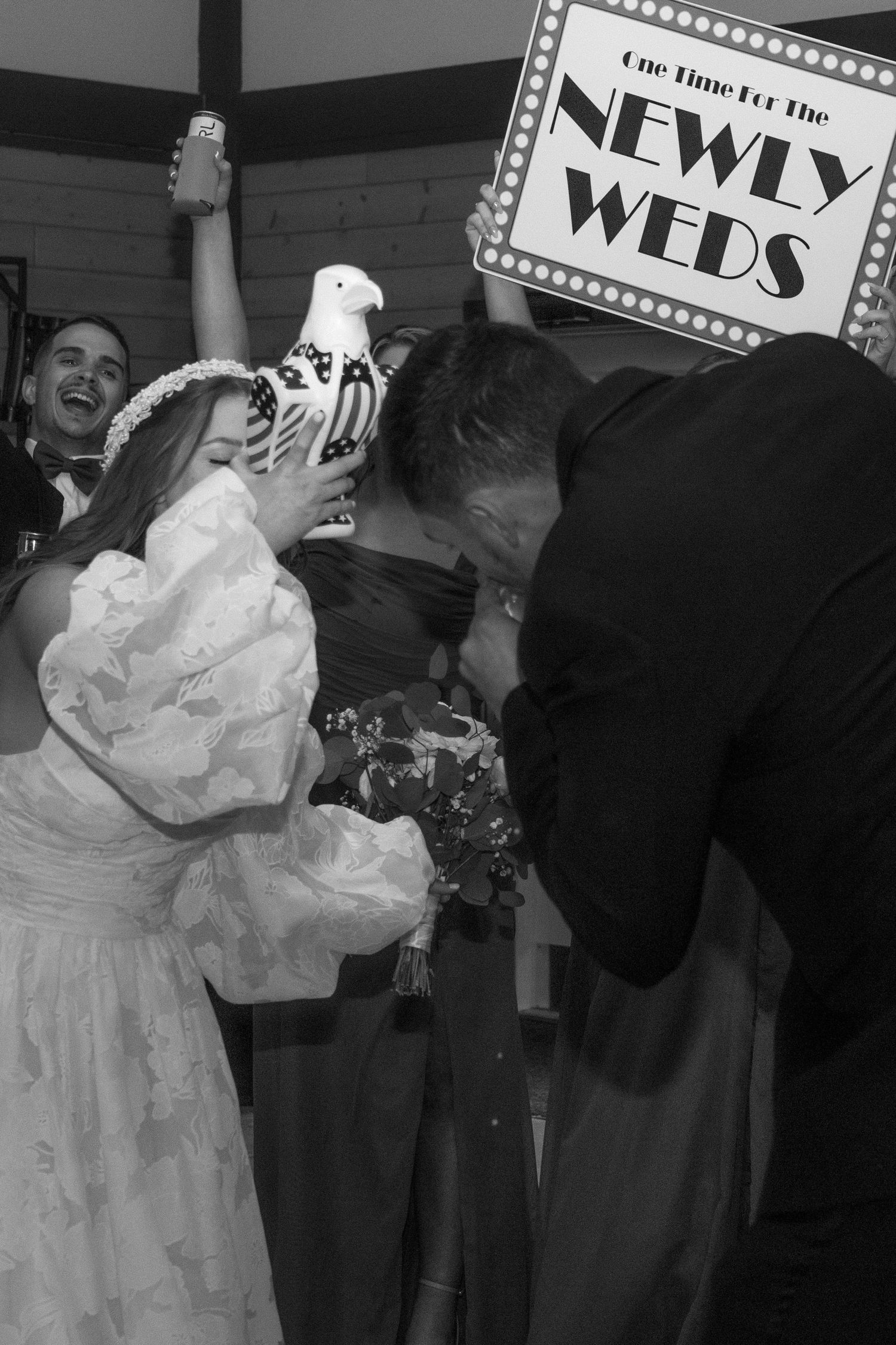 A vintage-styled wedding reception with newlyweds dancing among guests holding celebration signs.
