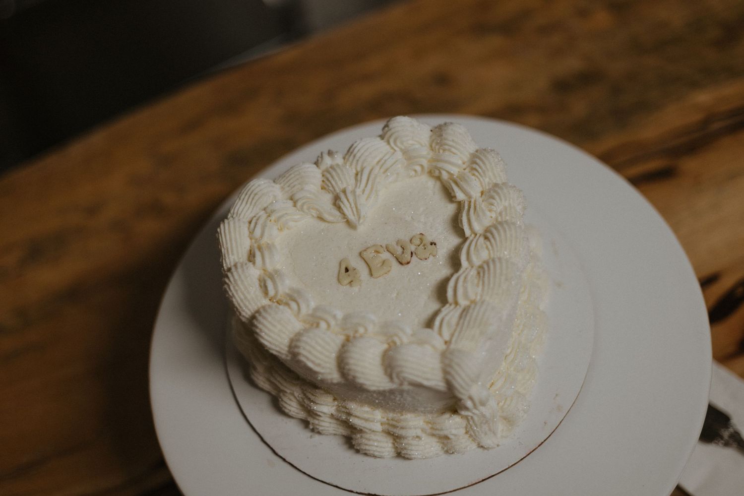 An elegant white wedding cake with delicate floral decorations displayed on a wooden surface.