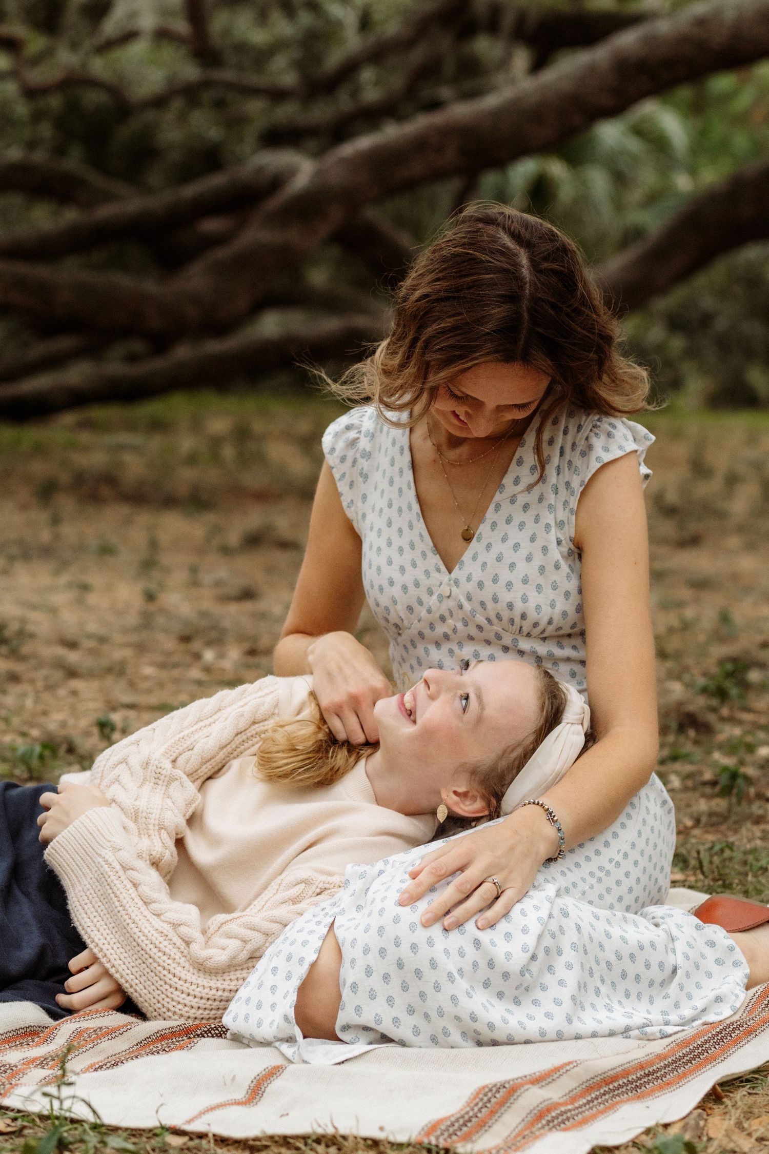 Mother and child sharing peaceful moment together on blanket under tree.