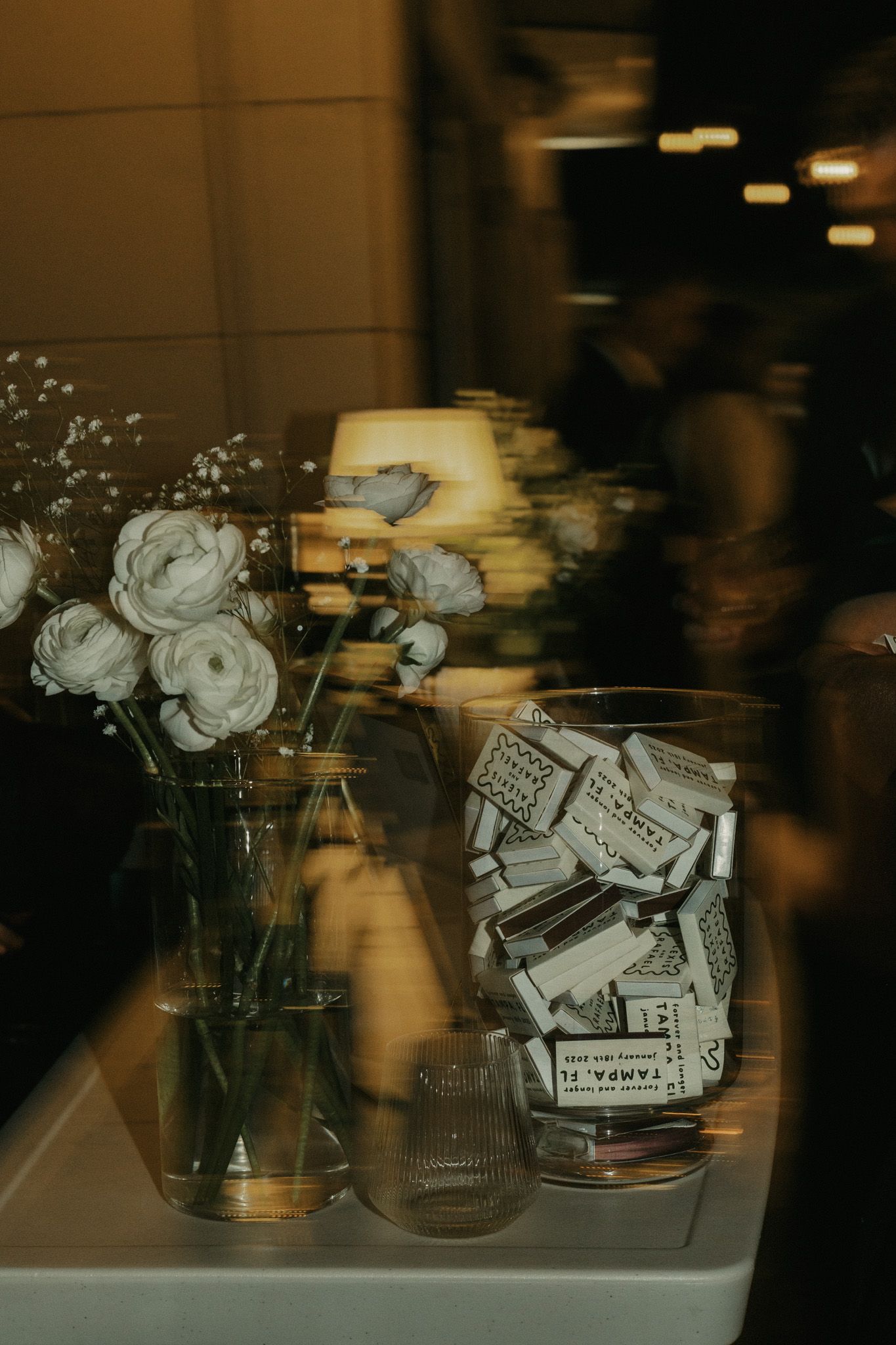 Mason jars filled with white roses and dollar bills in moody lighting.