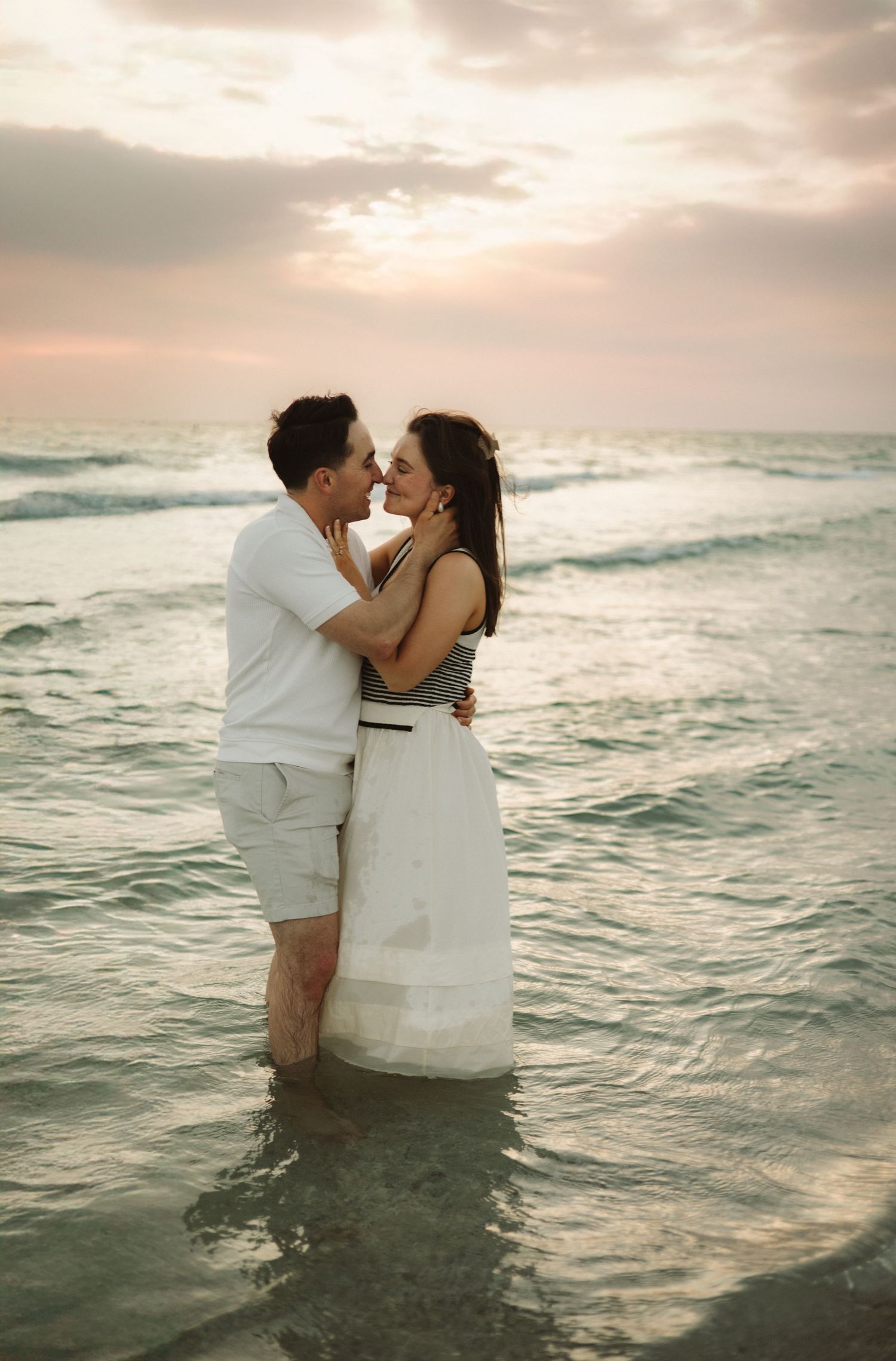 Couple sharing an intimate moment in the ocean during sunset.