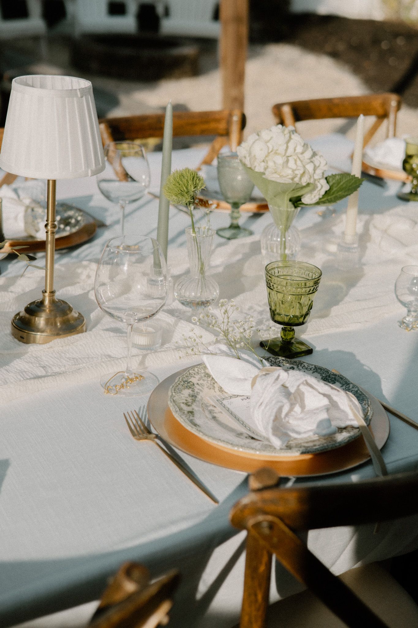 Elegant table settings with crystal glassware, white linens, and green accents at a wedding reception.