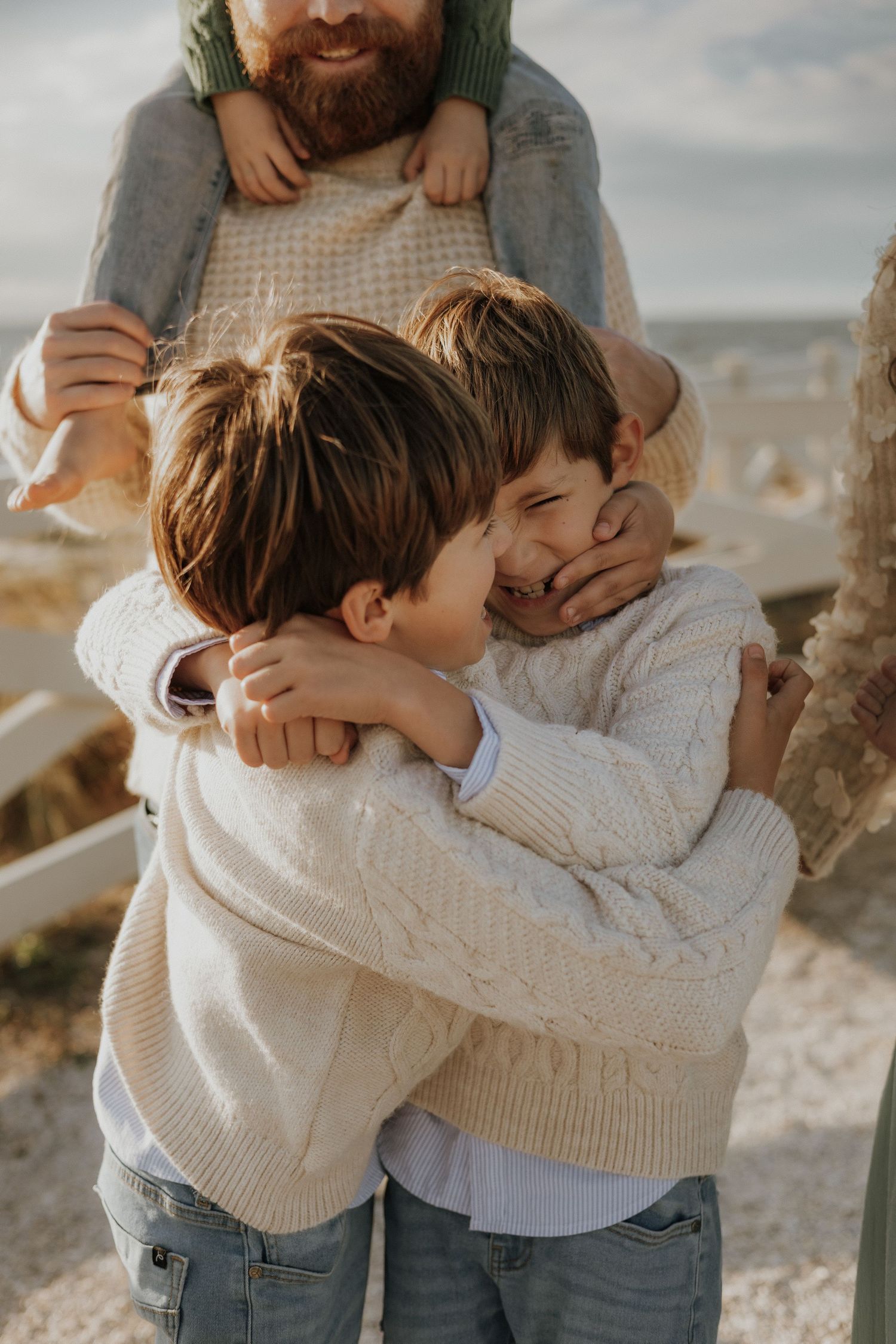 Close-up of parent and child embracing while wearing cream-colored knit sweaters.