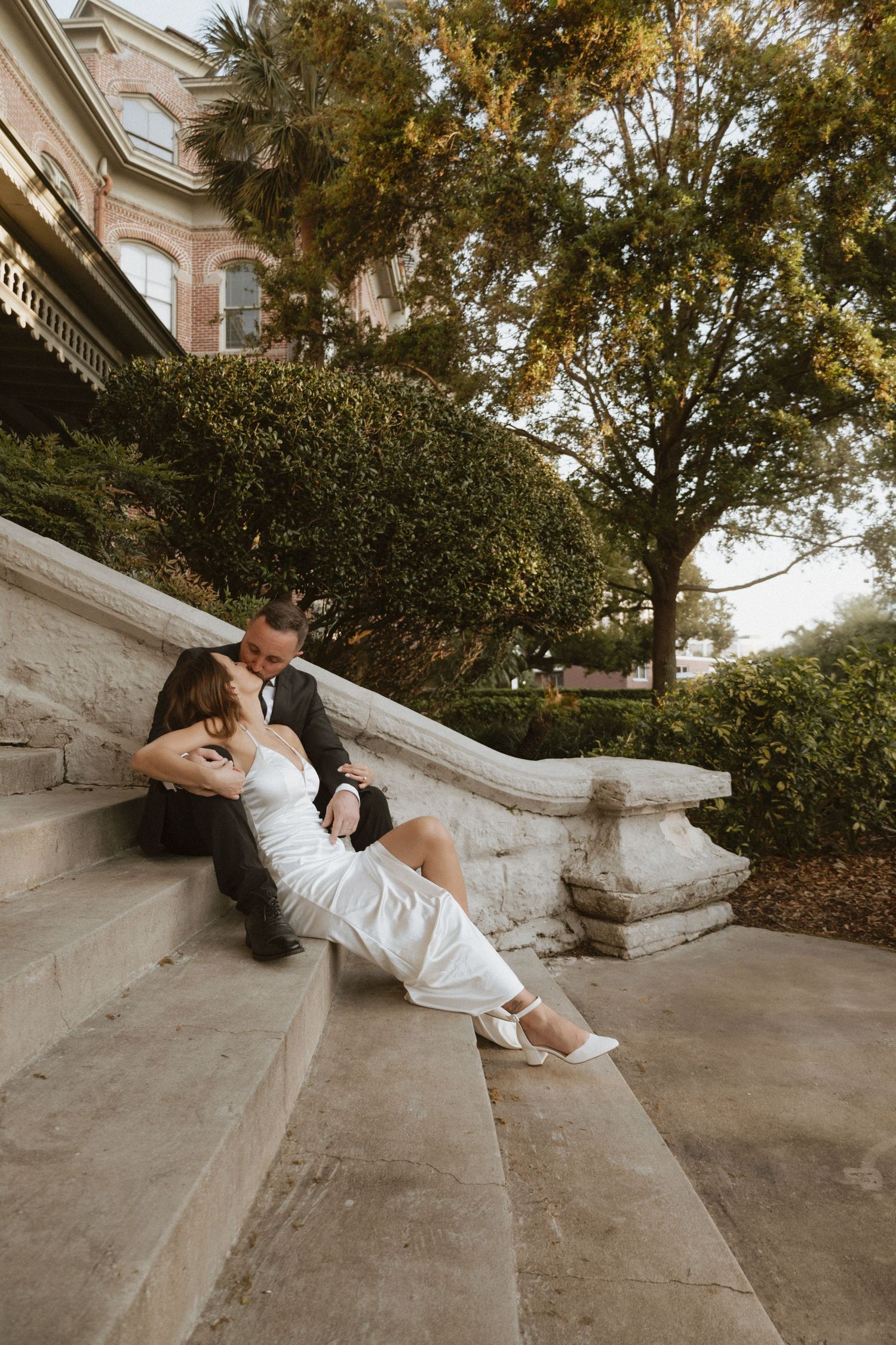 Series of romantic poses on concrete steps near historic building.