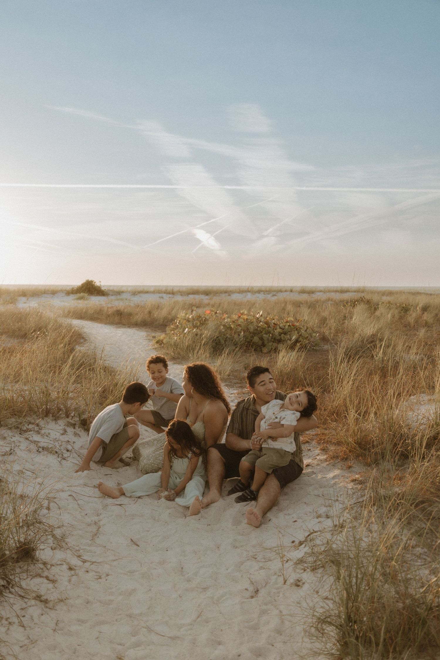 Group lying in sandy dunes during sunset beach photoshoot.