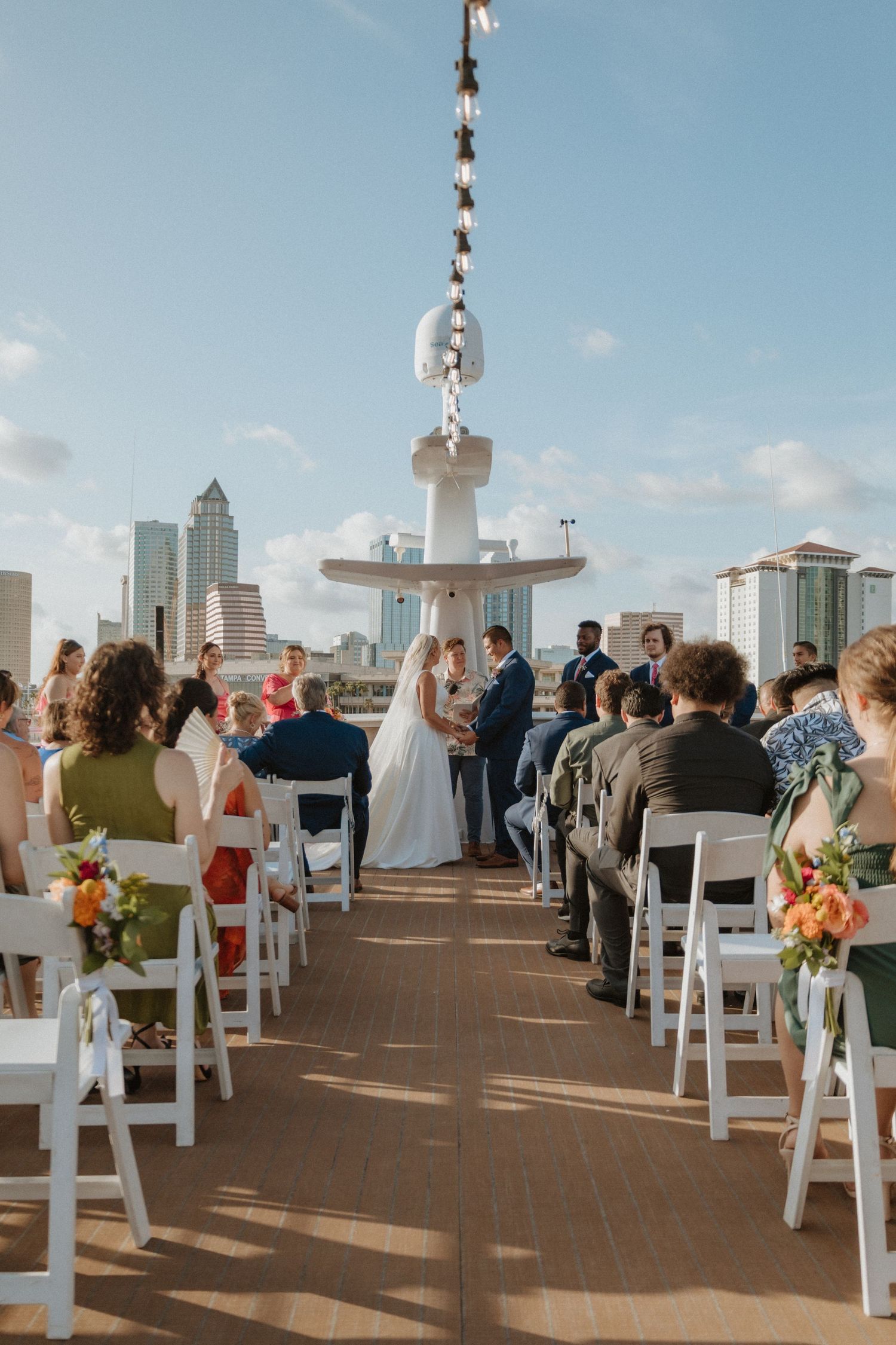 Rooftop wedding ceremony setup with white chairs and city skyline backdrop.